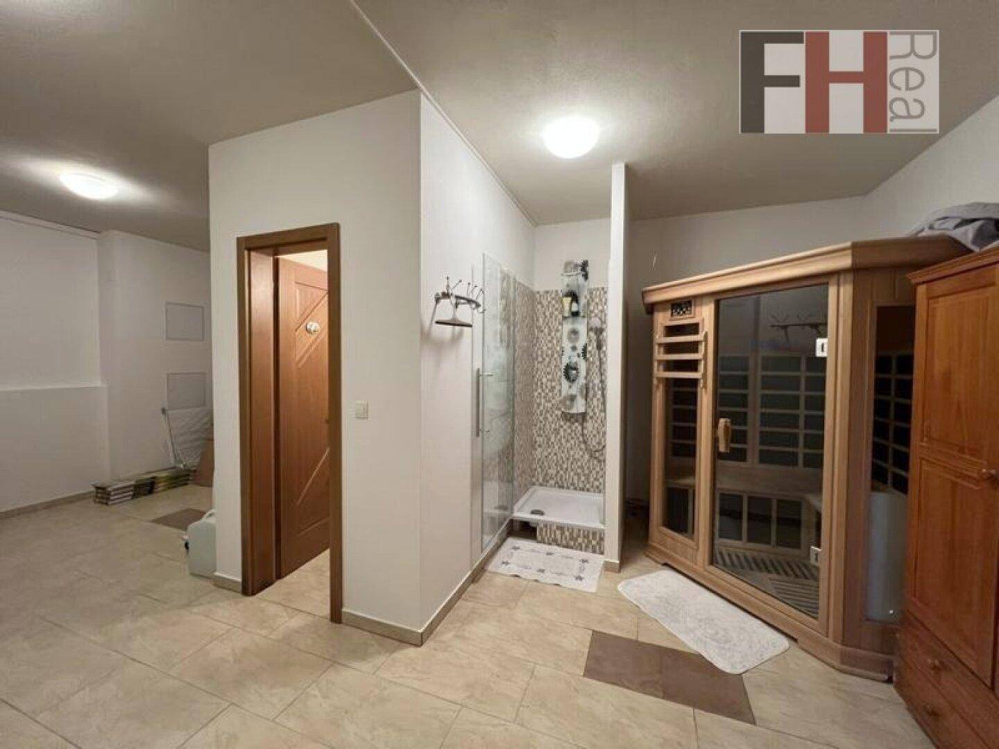Wellnessbereich im Untergeschoss mit Duschkabine und einer holzvertäfelten Sauna.