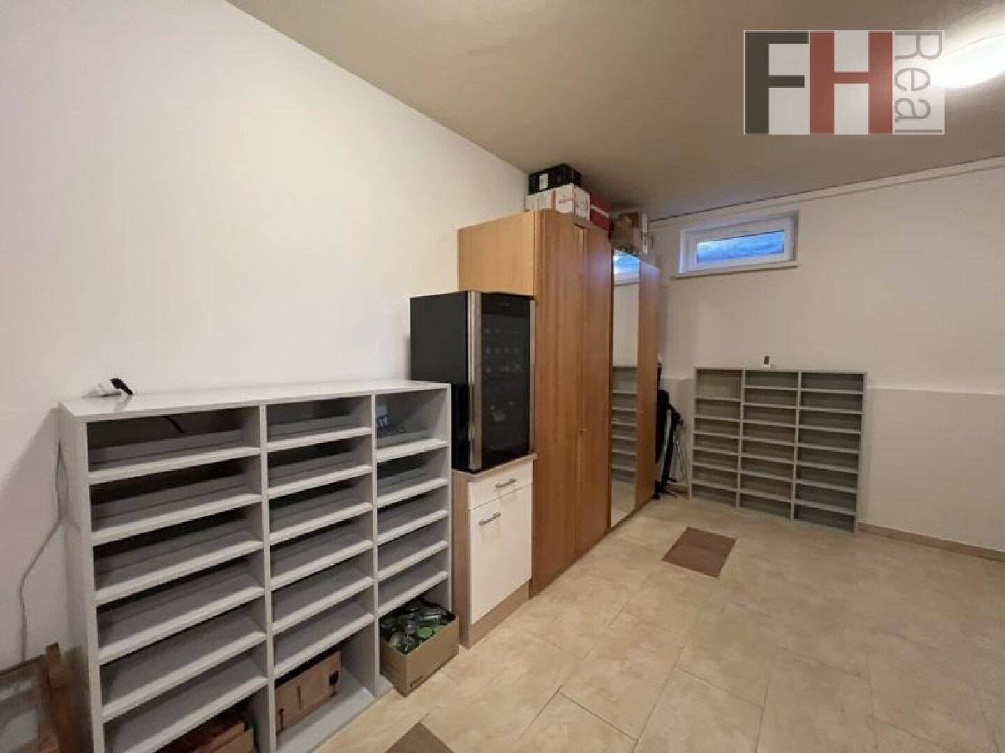 Geräumiger Abstellraum im Untergeschoss mit Regalen, Schränken und kleinem Fenster.