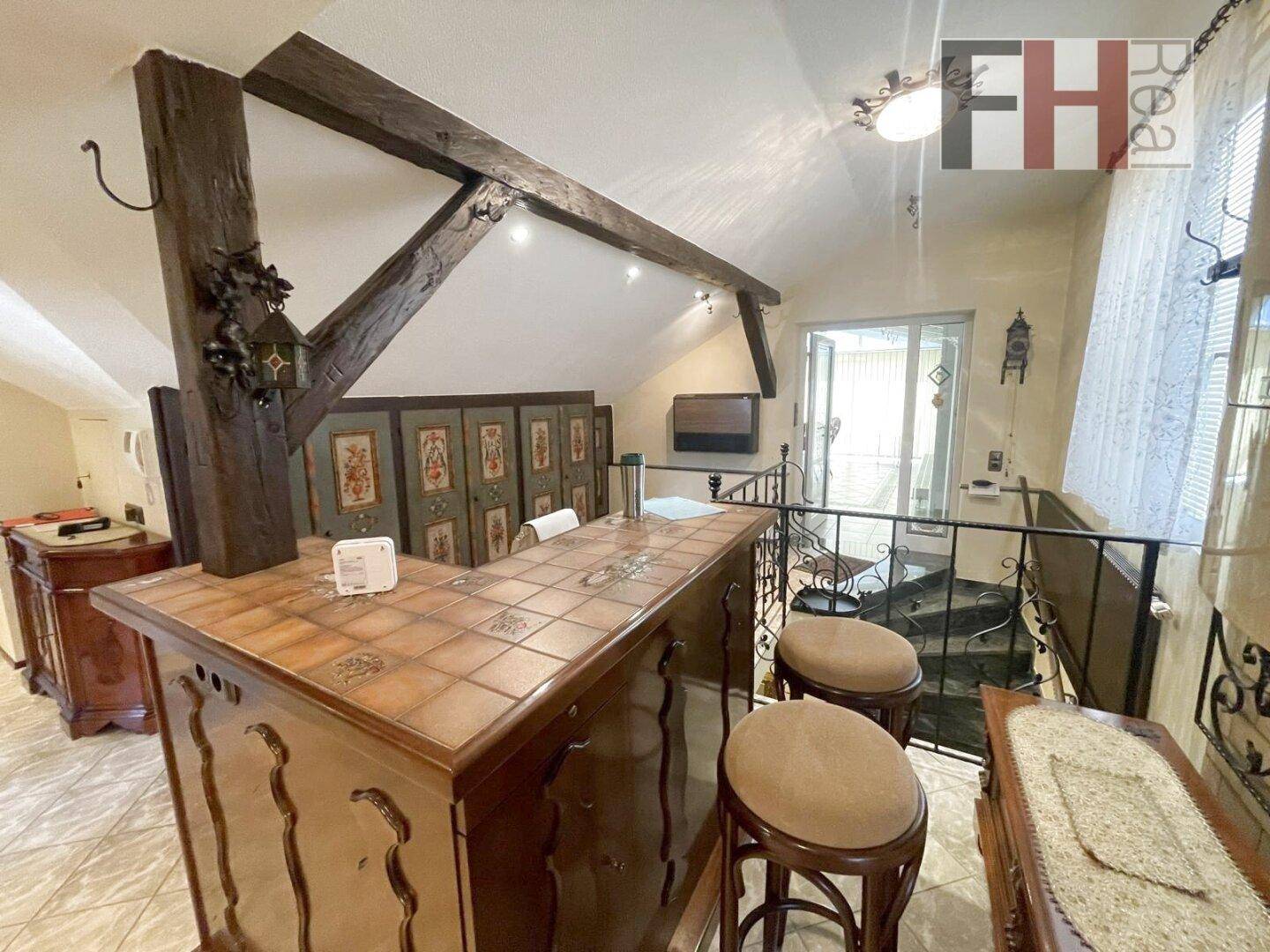 Barbereich mit Holzbalken und Fliesenboden, offen zu einem weiteren Wohnbereich.