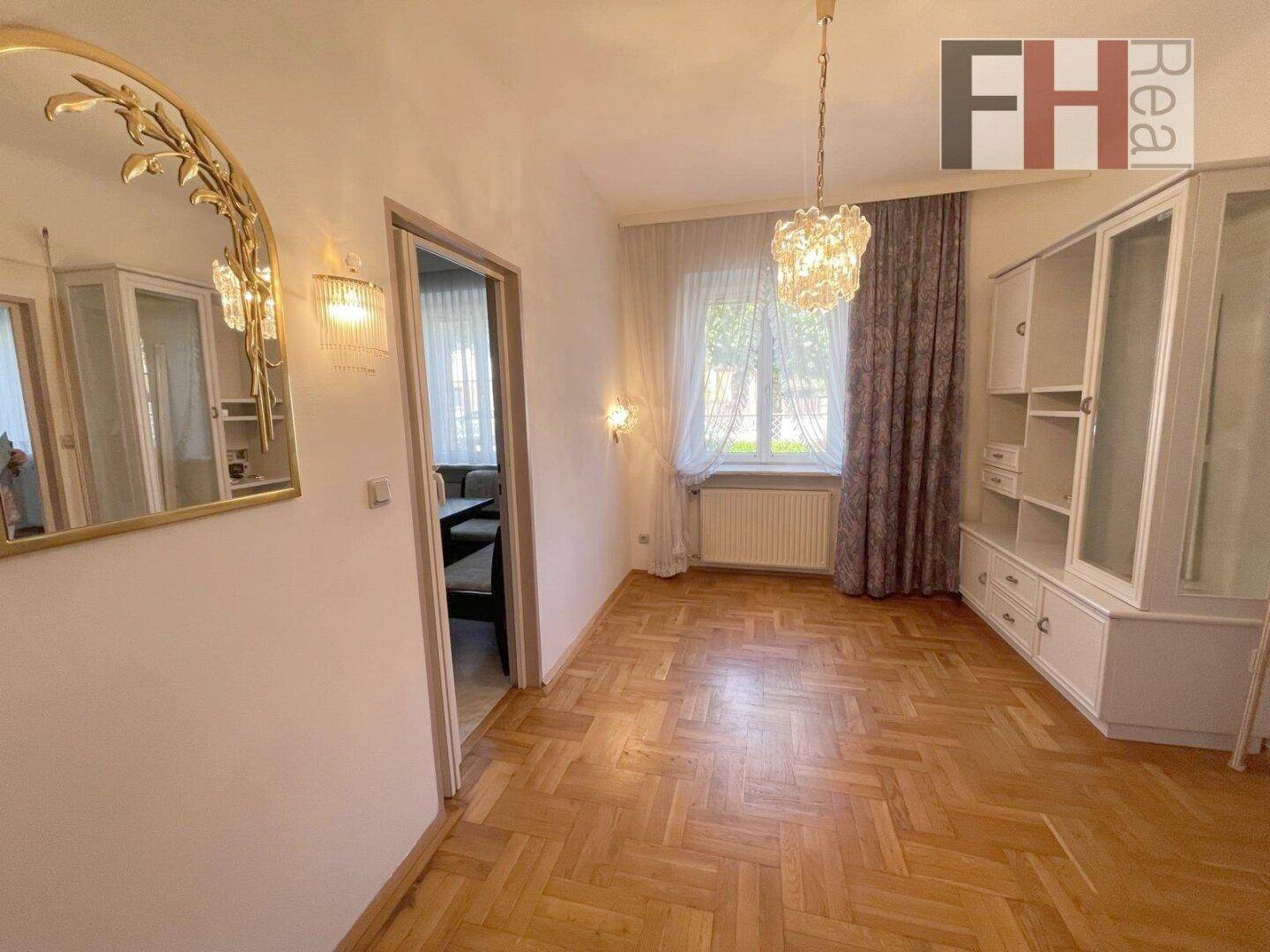 Helles Zimmer mit Parkettboden, dekorativem Spiegel und Einbauschränken.