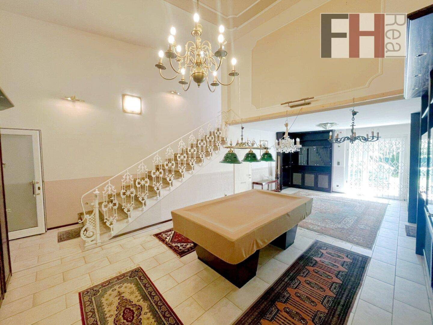 Großer Eingangsbereich mit Billardtisch, hoher Decke und eleganter Treppe.
