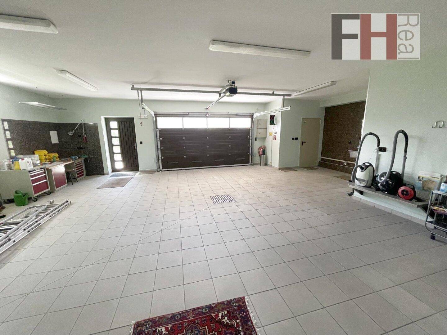 Geräumige Garage mit Fliesenboden, automatischem Tor und viel Stauraum.
