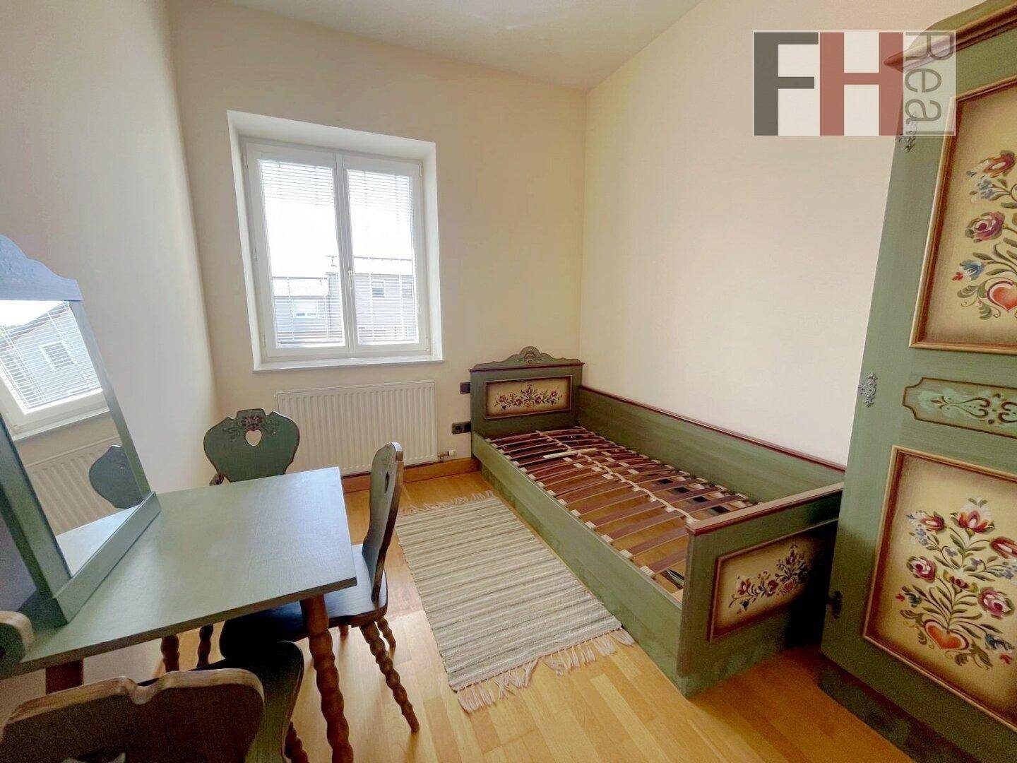 Kleines Schlafzimmer mit Holzboden, Fenster und traditionellen Möbeln.