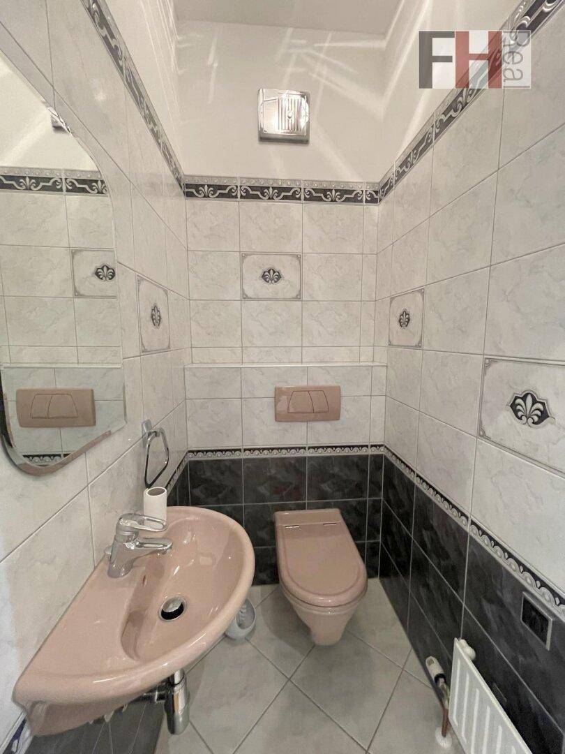 Kleines Gäste-WC mit Waschbecken, Toilette und Fliesen an den Wänden.