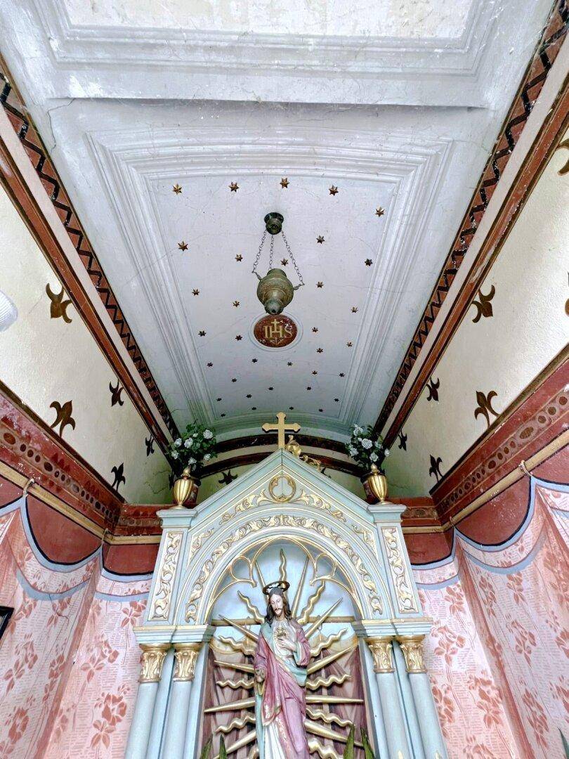 Blick zur reich verzierten Decke eines Andachtsraumes mit Hängelampe und Sternenmuster.