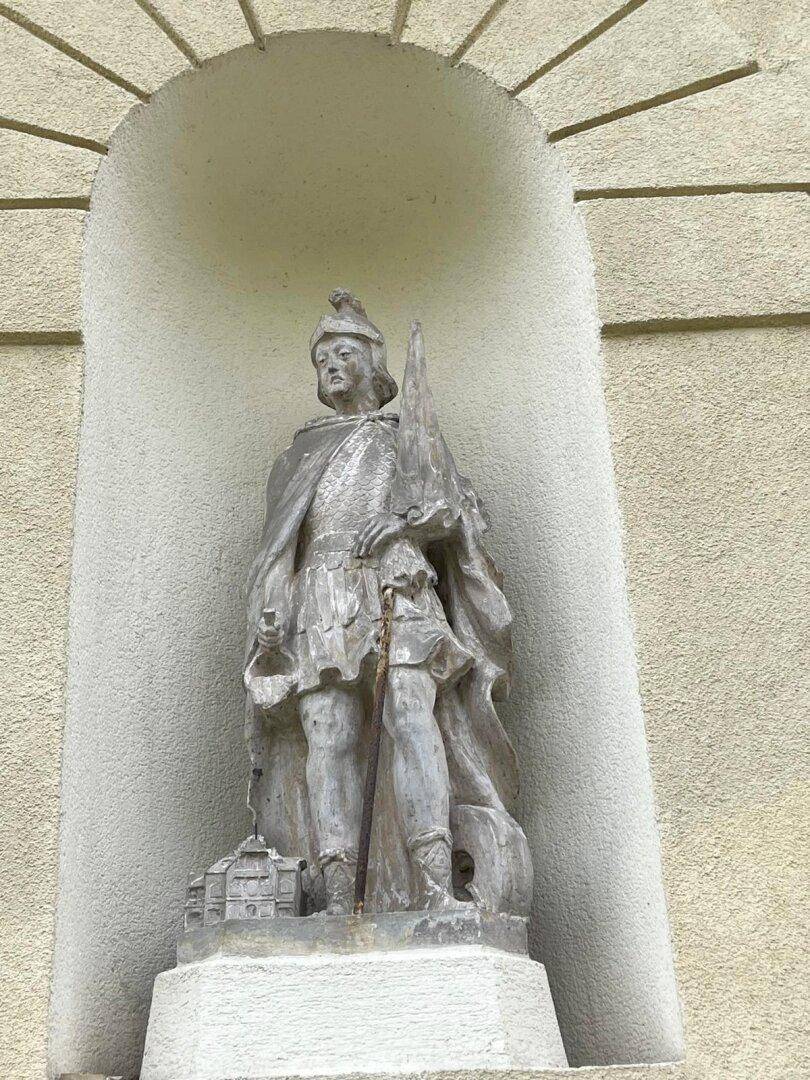 Steinstatue eines Ritters in einer Nische an der historischen Gebäudefassade.