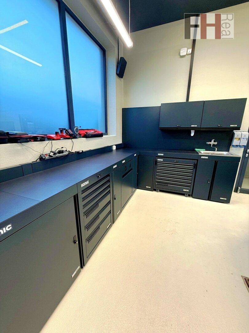 Detailansicht der schwarzen Einbauschränke und Arbeitsflächen in der Werkstatt, mit einem großen Fenster für natürliches Licht.