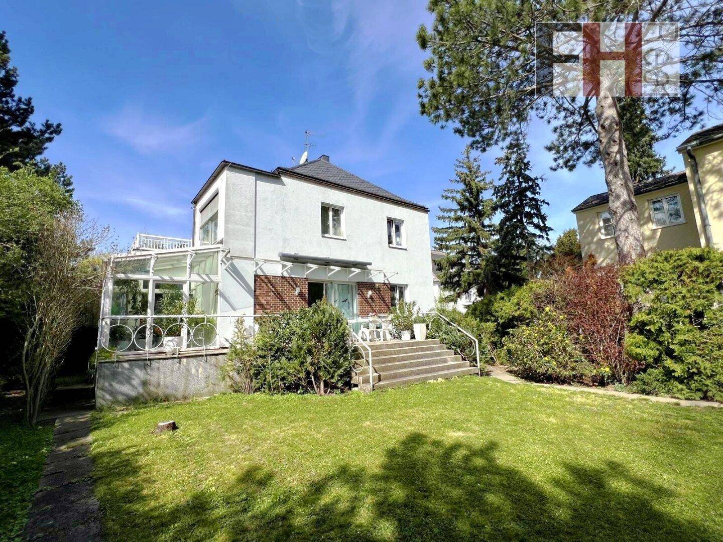 Rückansicht des Hauses mit gepflegtem Garten und sonniger Terrasse.