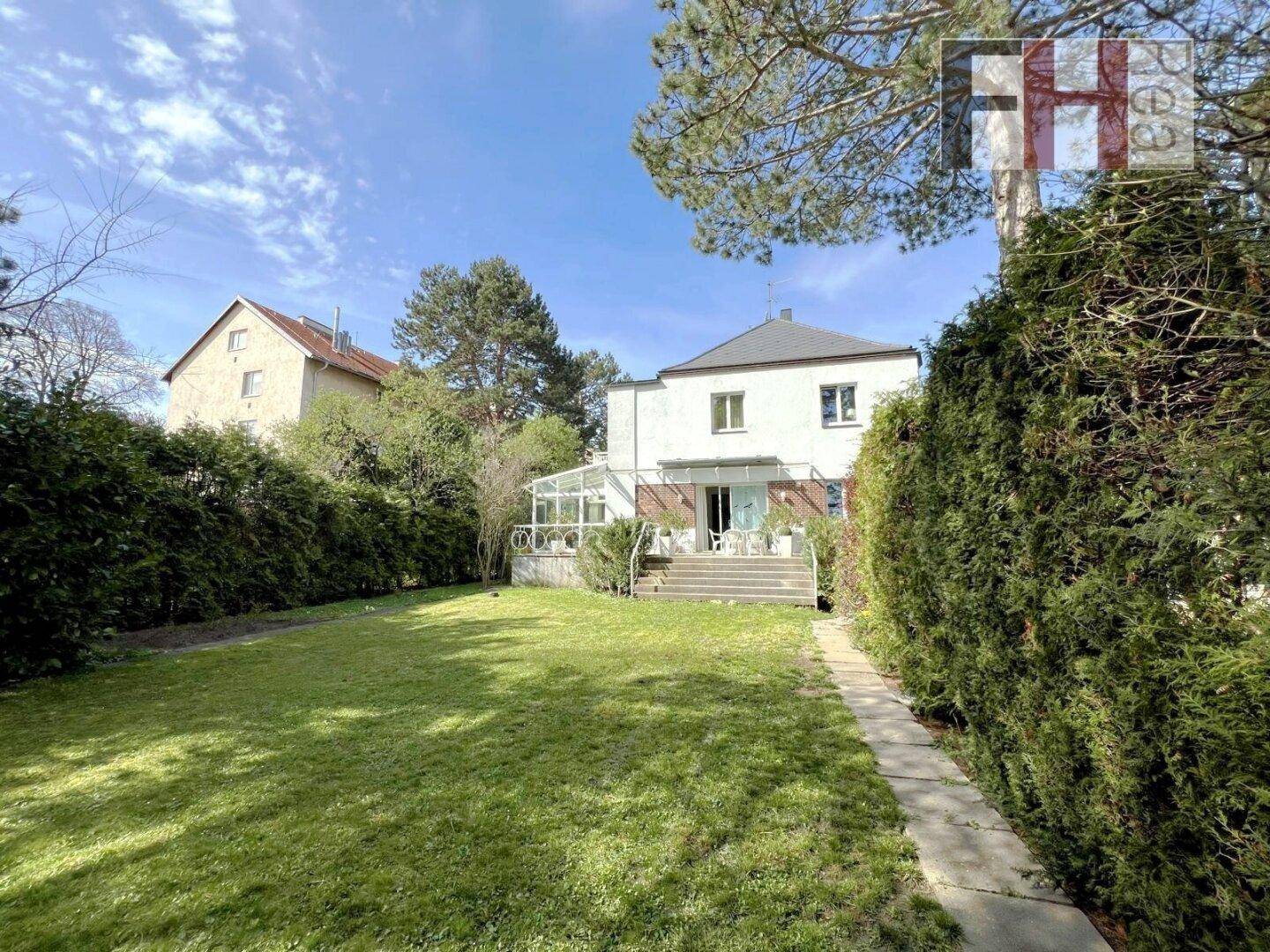 Weitläufiger Gartenbereich mit Rasenfläche und Blick auf die Hausrückseite.