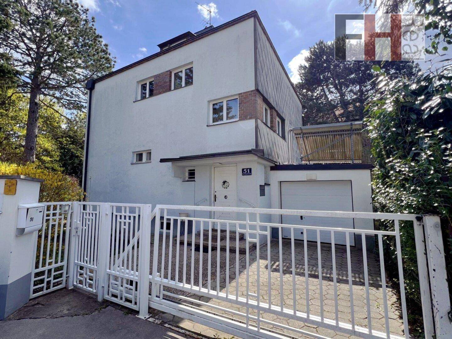 Vorderansicht des Hauses mit Einfahrt, Garage und weißem Zaun.