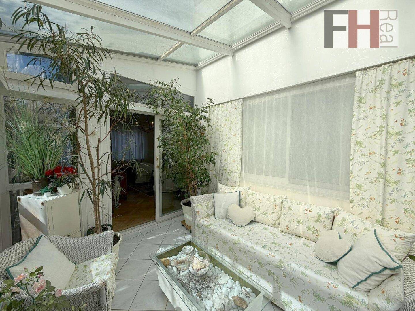 Heller Wintergarten mit Fliesenboden, Pflanzen und Zugang zum Innenbereich.