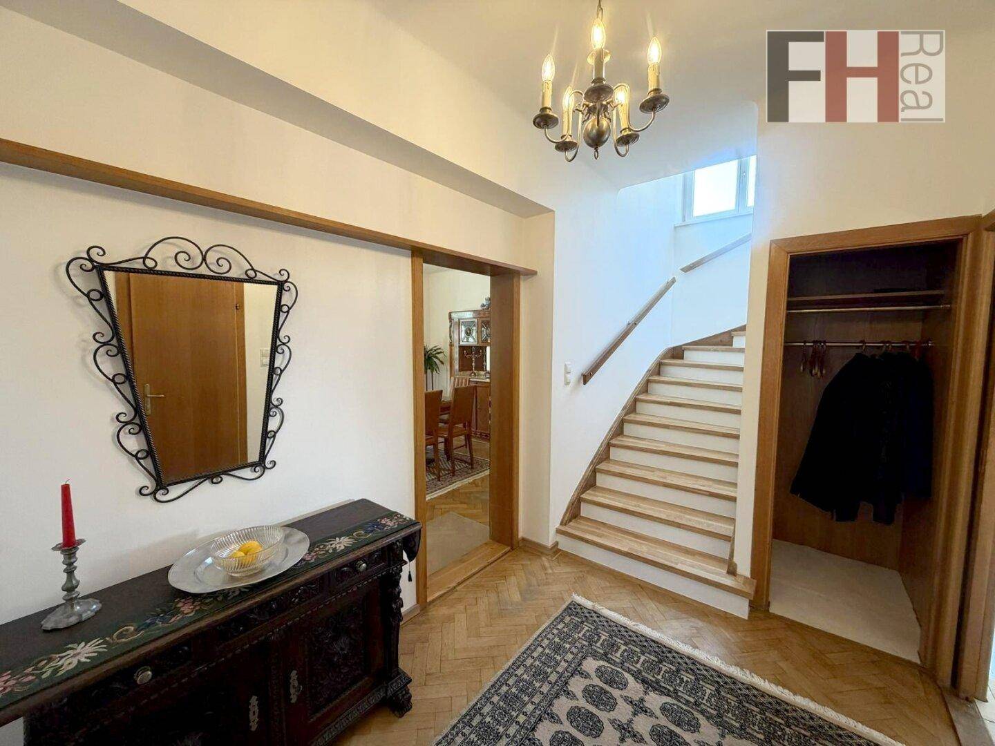 Heller Eingangsbereich mit Holztreppe, Garderobe und Parkettboden.