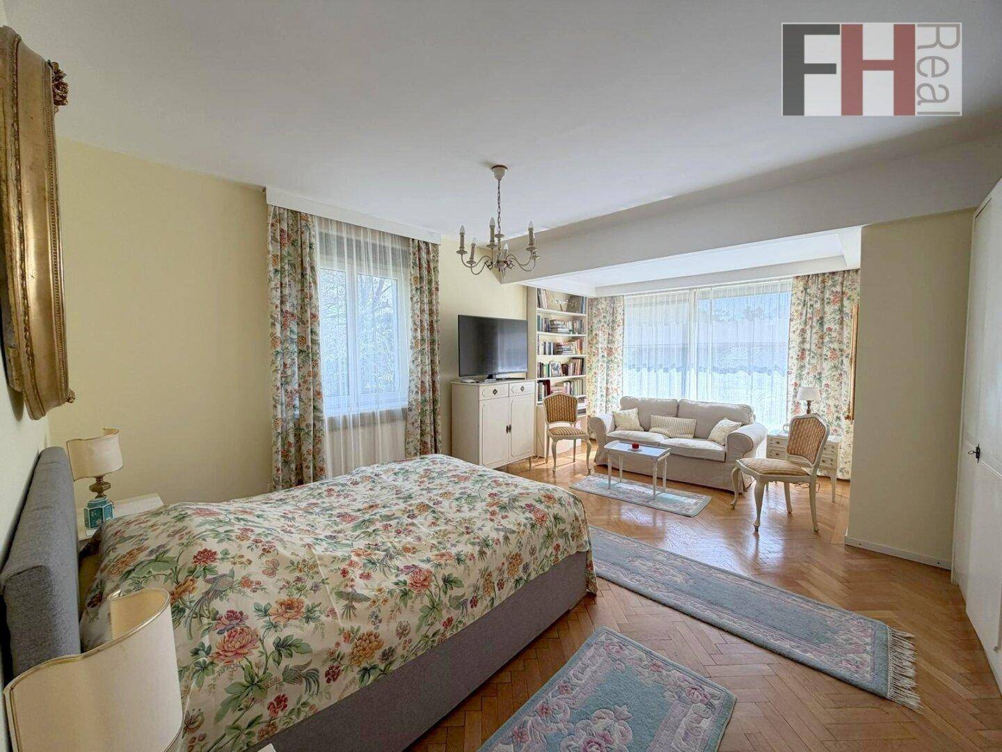 Geräumiges Schlafzimmer mit Parkettboden, Sitzbereich und Bücherregal.