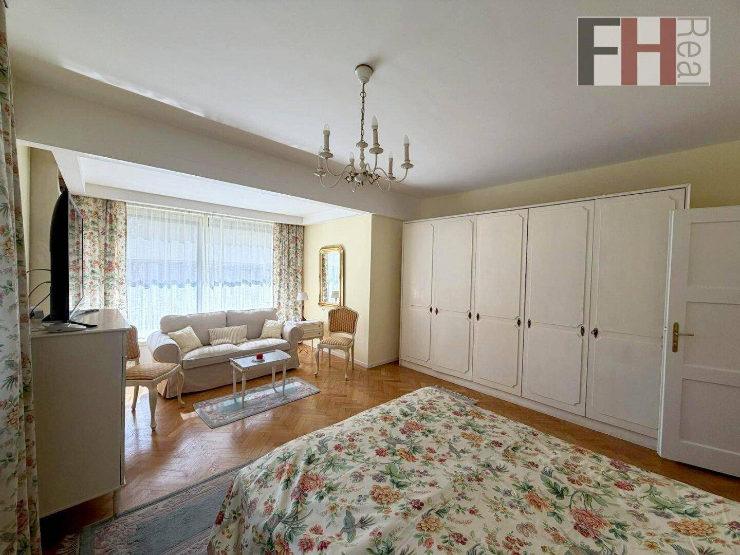 Helles Schlafzimmer mit Parkettboden, großen Fenstern und Einbauschränken.