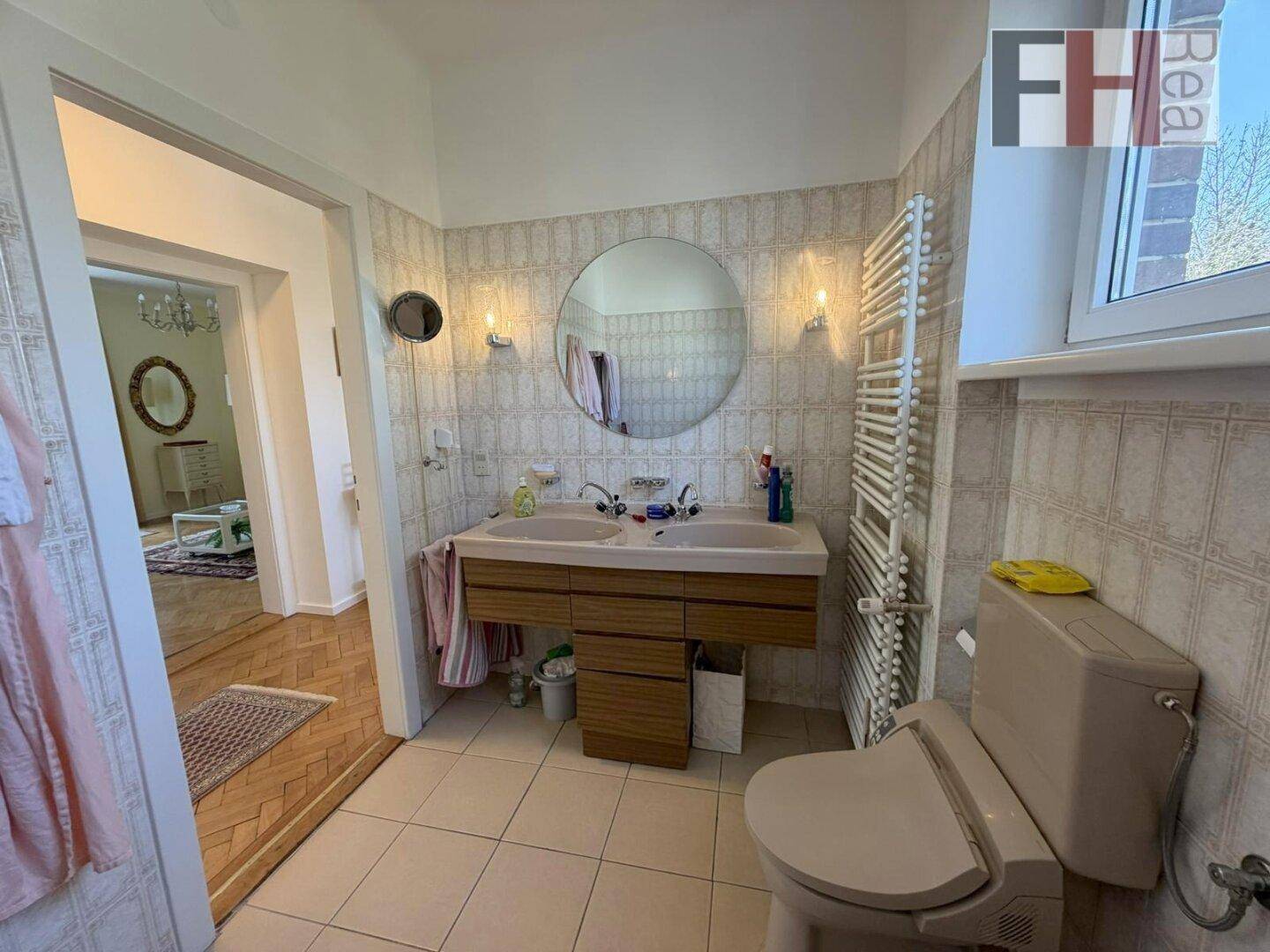 Badezimmer mit Doppelwaschbecken, WC und beheiztem Handtuchhalter.
