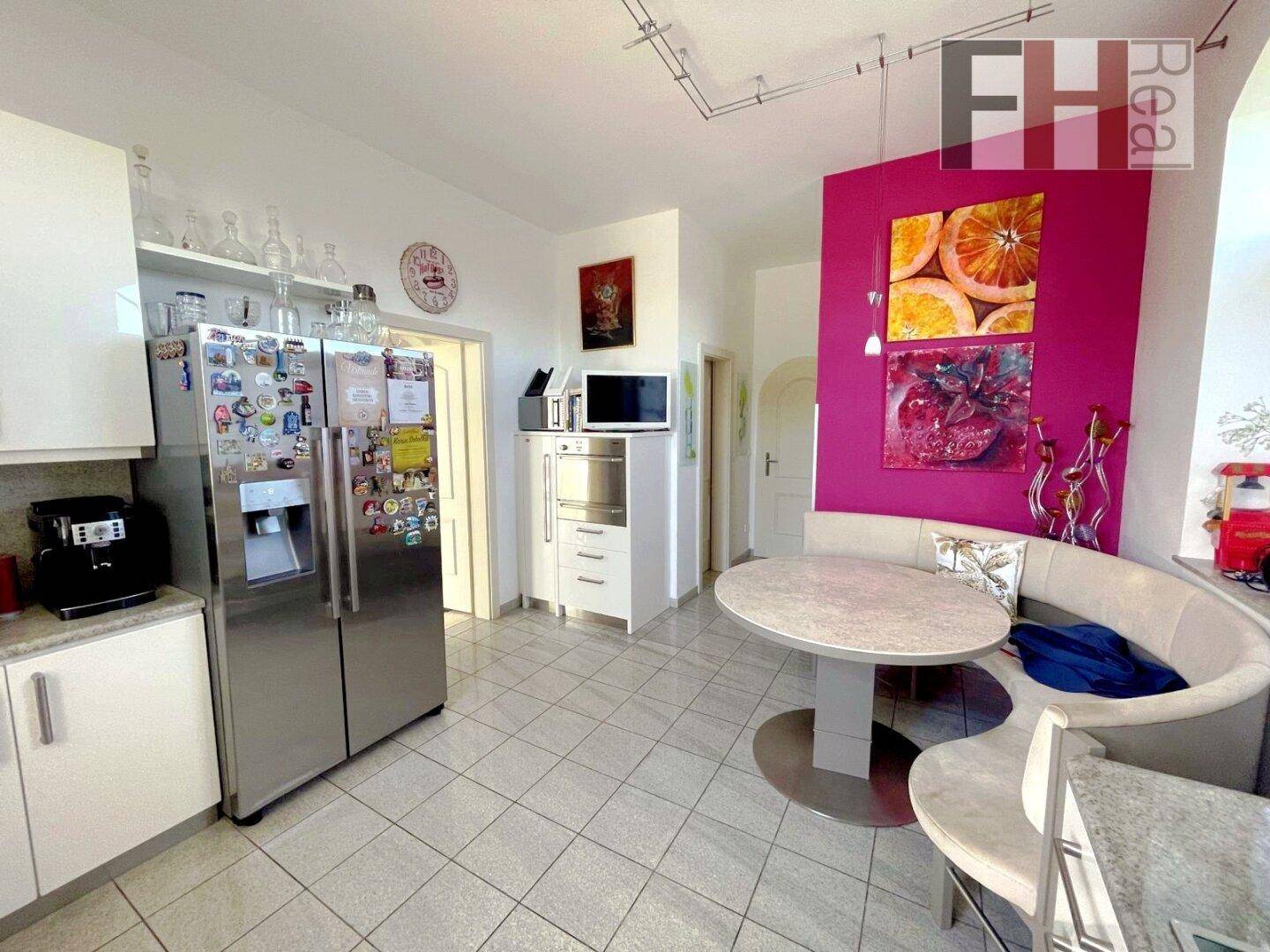 Geräumige Küche mit großem Kühlschrank, modernen Geräten und farbiger Akzentwand.
