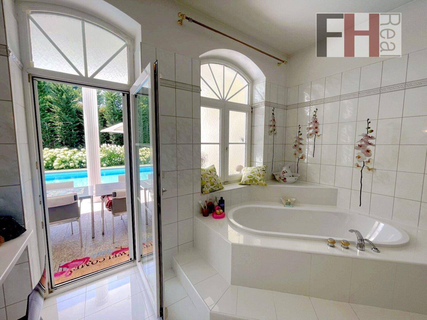 Geräumiges Badezimmer mit Badewanne und direktem Zugang zum Außenbereich mit Pool.