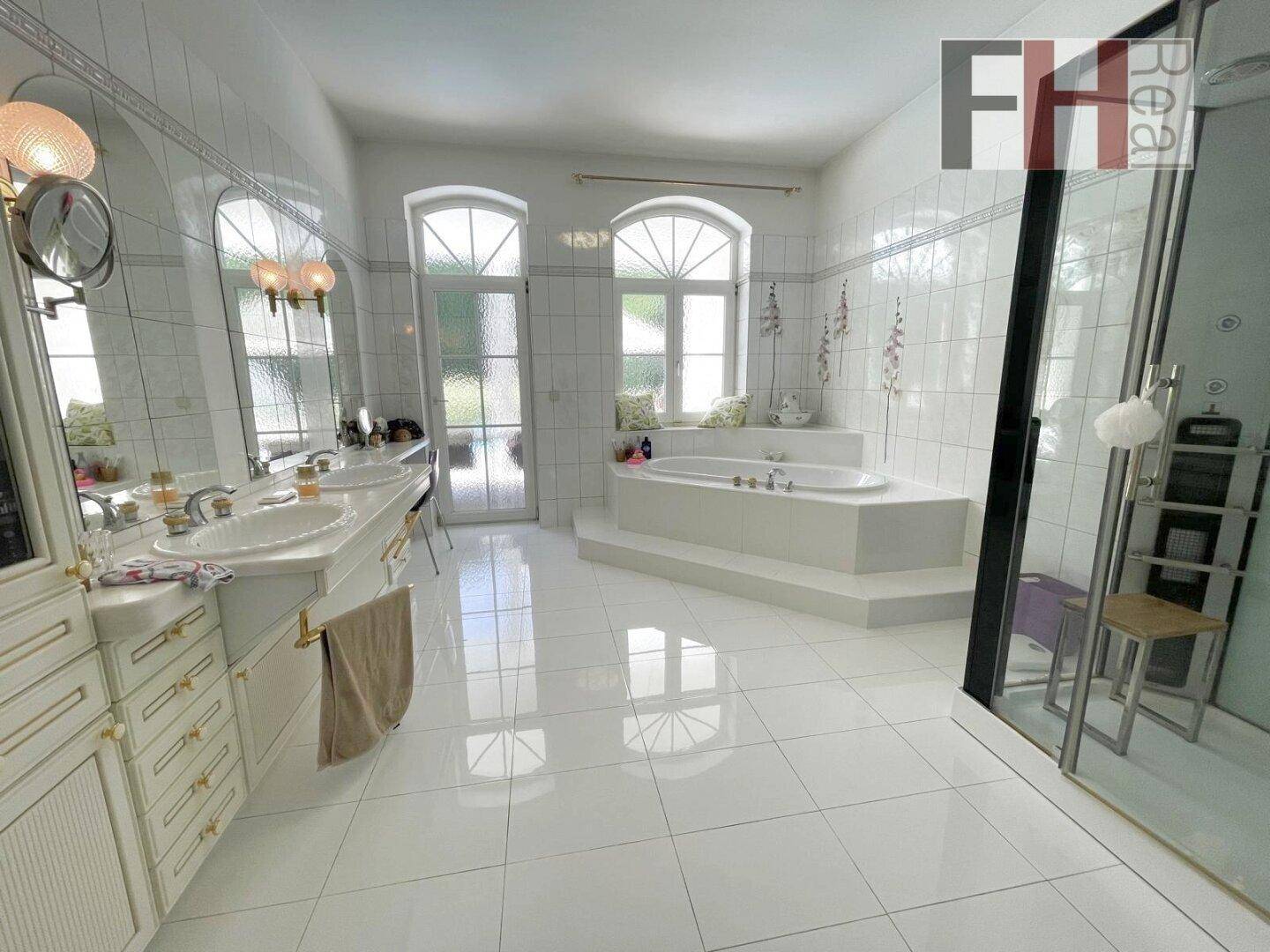 Großes Badezimmer mit Doppelwaschbecken, Badewanne und separater Dusche, hell gefliest.