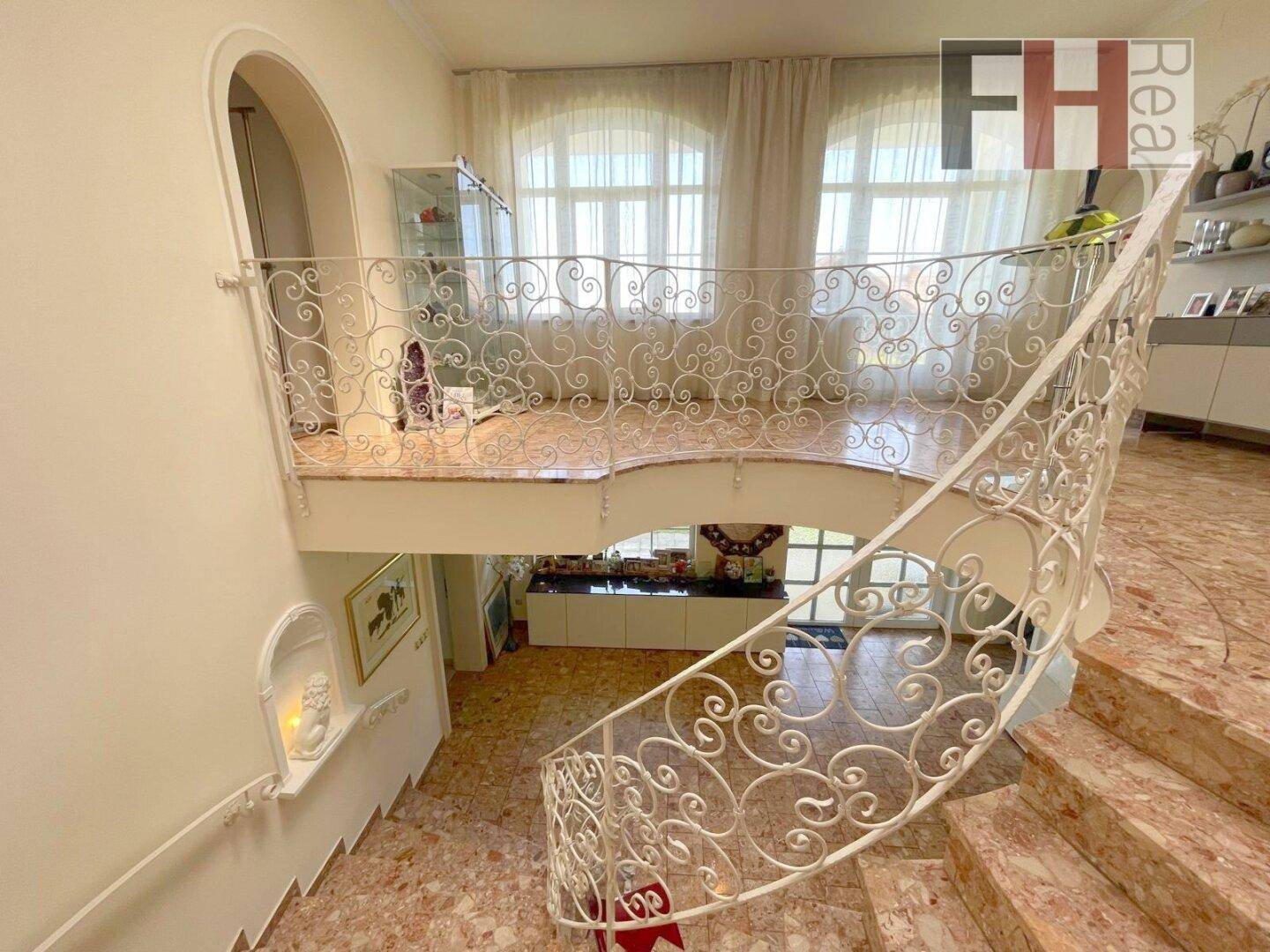 Oberer Flurbereich mit Blick auf die untere Etage und dekorativem schmiedeeisernem Geländer.