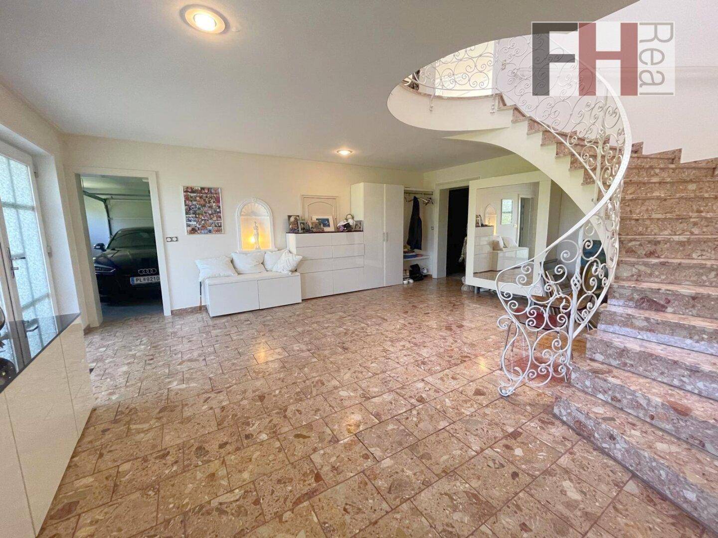 Heller Eingangsbereich mit eleganter Wendeltreppe und direktem Zugang zur Garage.