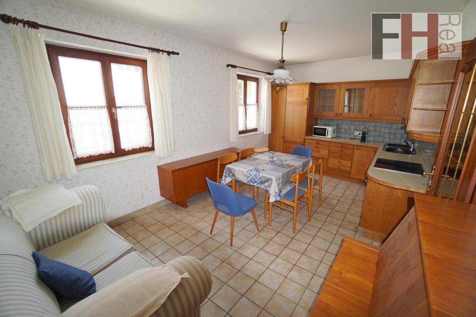 Wohnküche mit Holzschränken, Fliesenboden und einem Essbereich für die Familie.