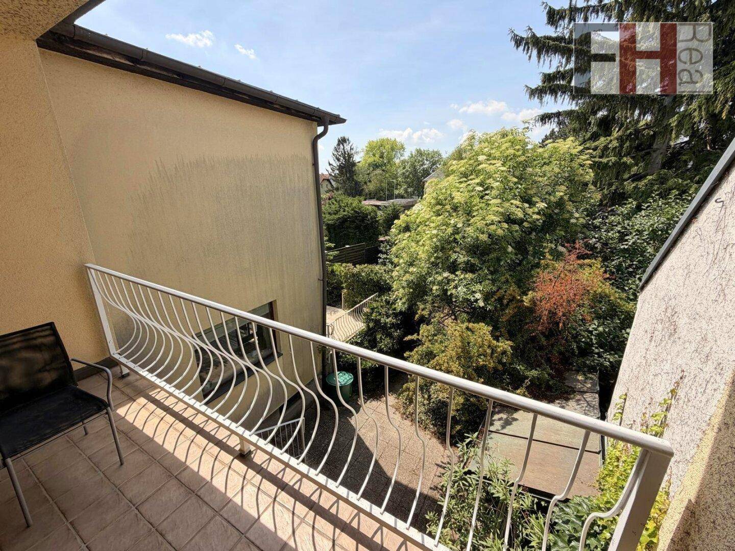 Balkon mit Fliesenboden und schmiedeeisernem Geländer, bietet Blick ins Grüne.
