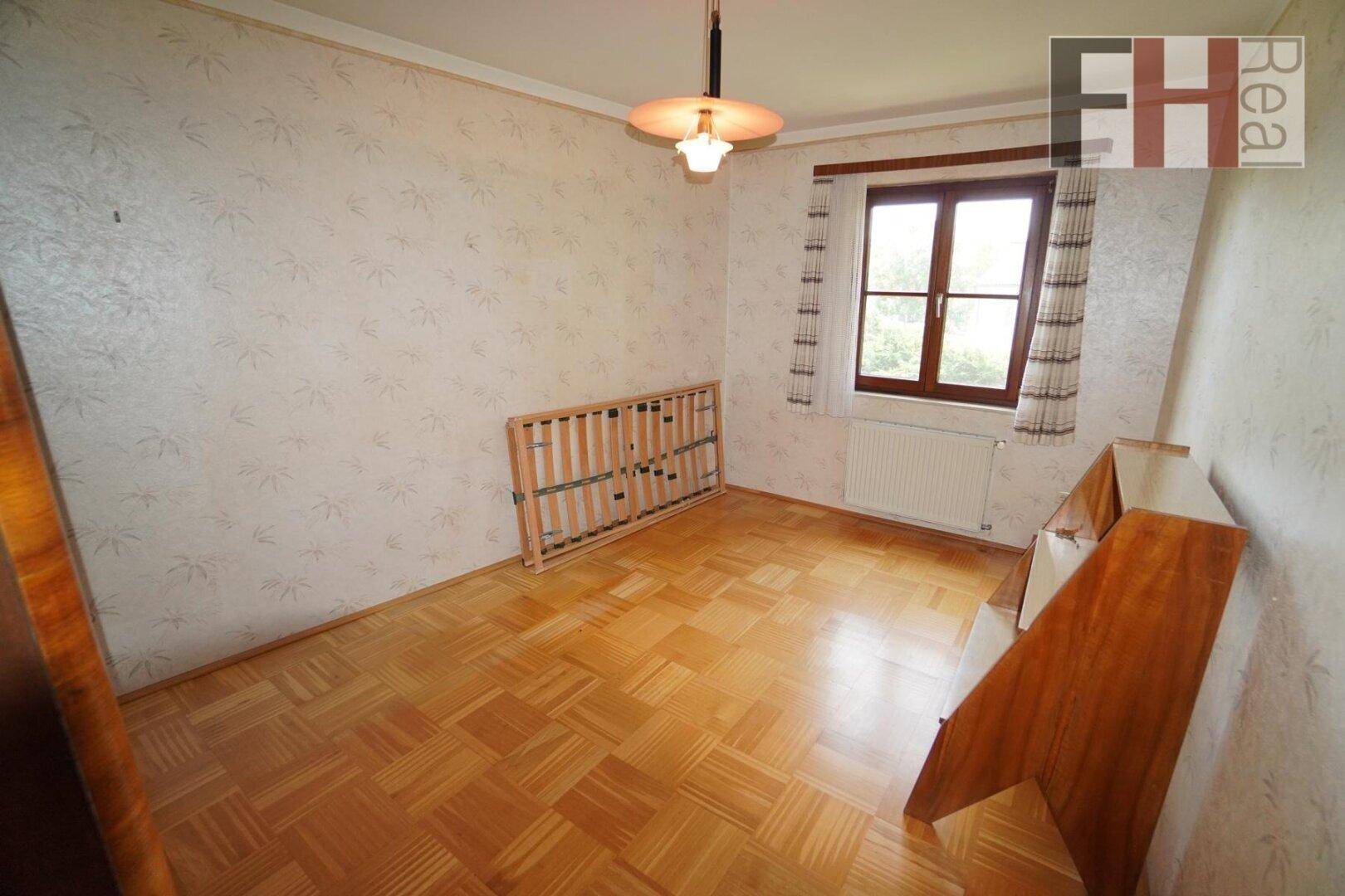 Leeres Schlafzimmer mit Parkettboden und Fenster, bereit zur individuellen Gestaltung.