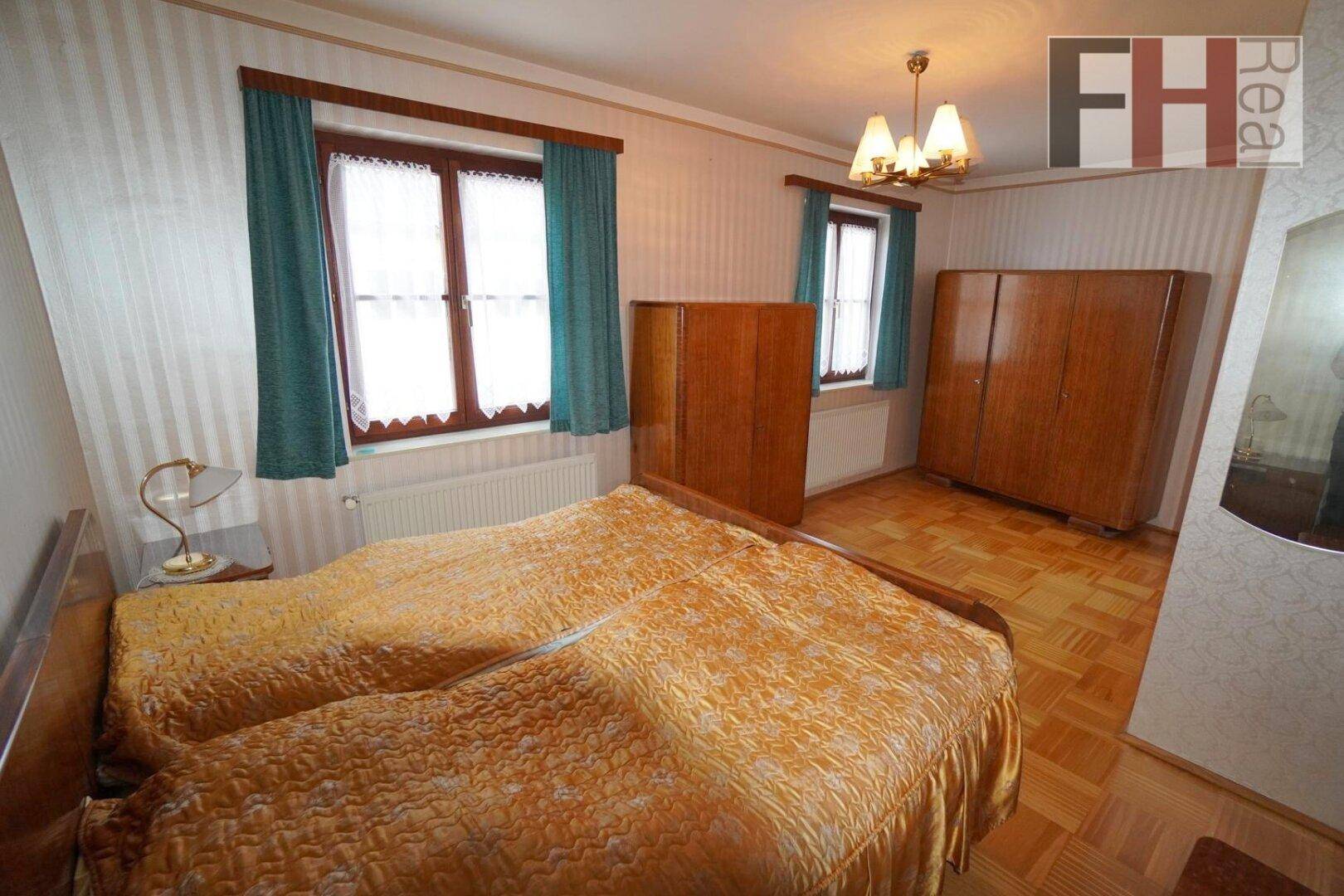 Schlafzimmer mit zwei Einzelbetten, Parkettboden und klassischen Holzschränken.