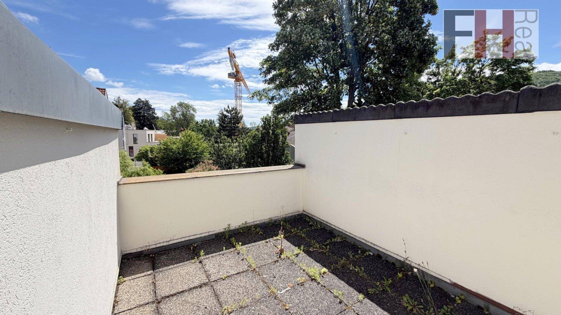 Kleine, ungenutzte Terrasse mit Betonplatten und Blick auf die Umgebung mit einem Baukran.