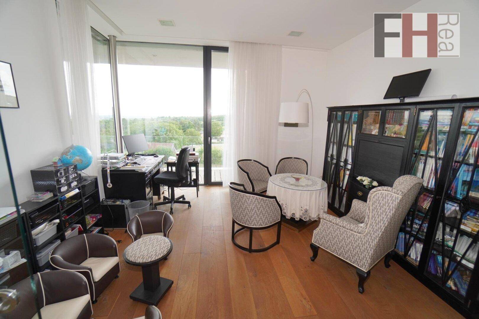 Helles Arbeitszimmer mit Holzboden, großen Fenstern und Blick ins Grüne.