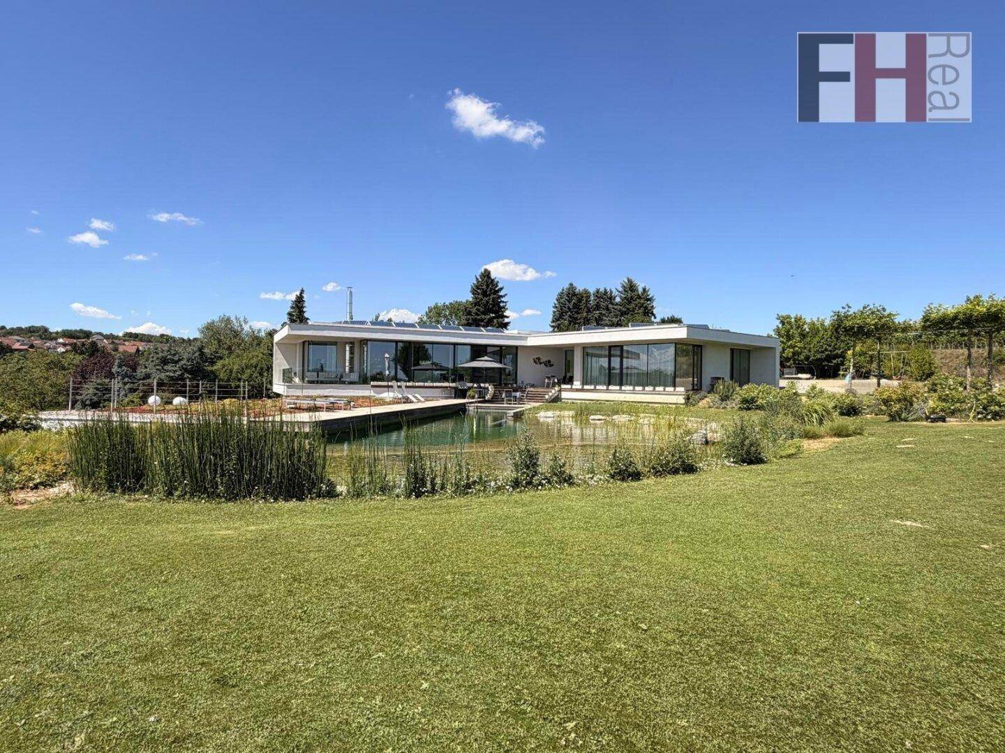 Weitläufiger Gartenbereich mit gepflegtem Rasen und moderner Villa im Hintergrund.