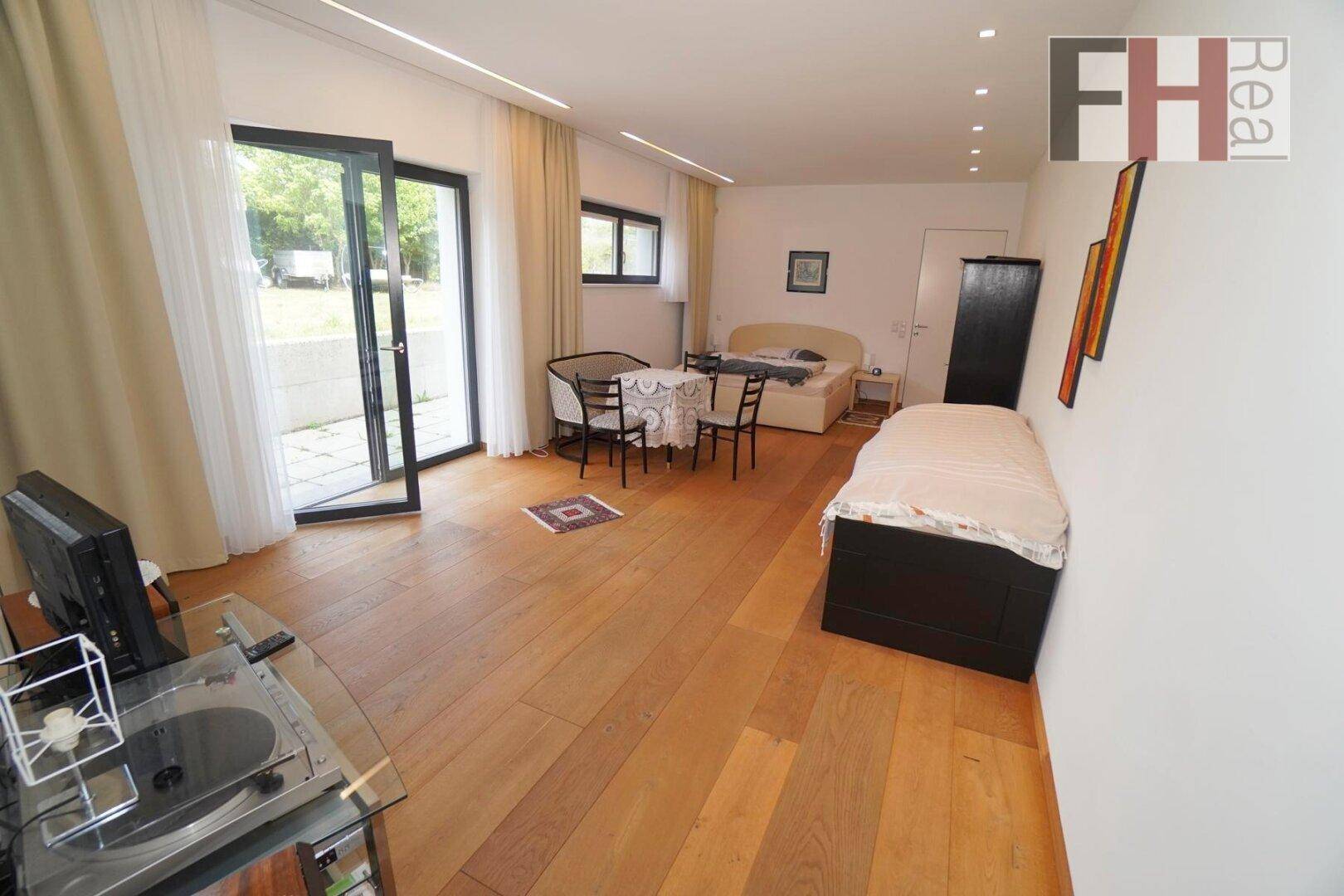 Geräumiges Schlafzimmer mit Holzboden, Zugang zum Garten und viel Tageslicht.