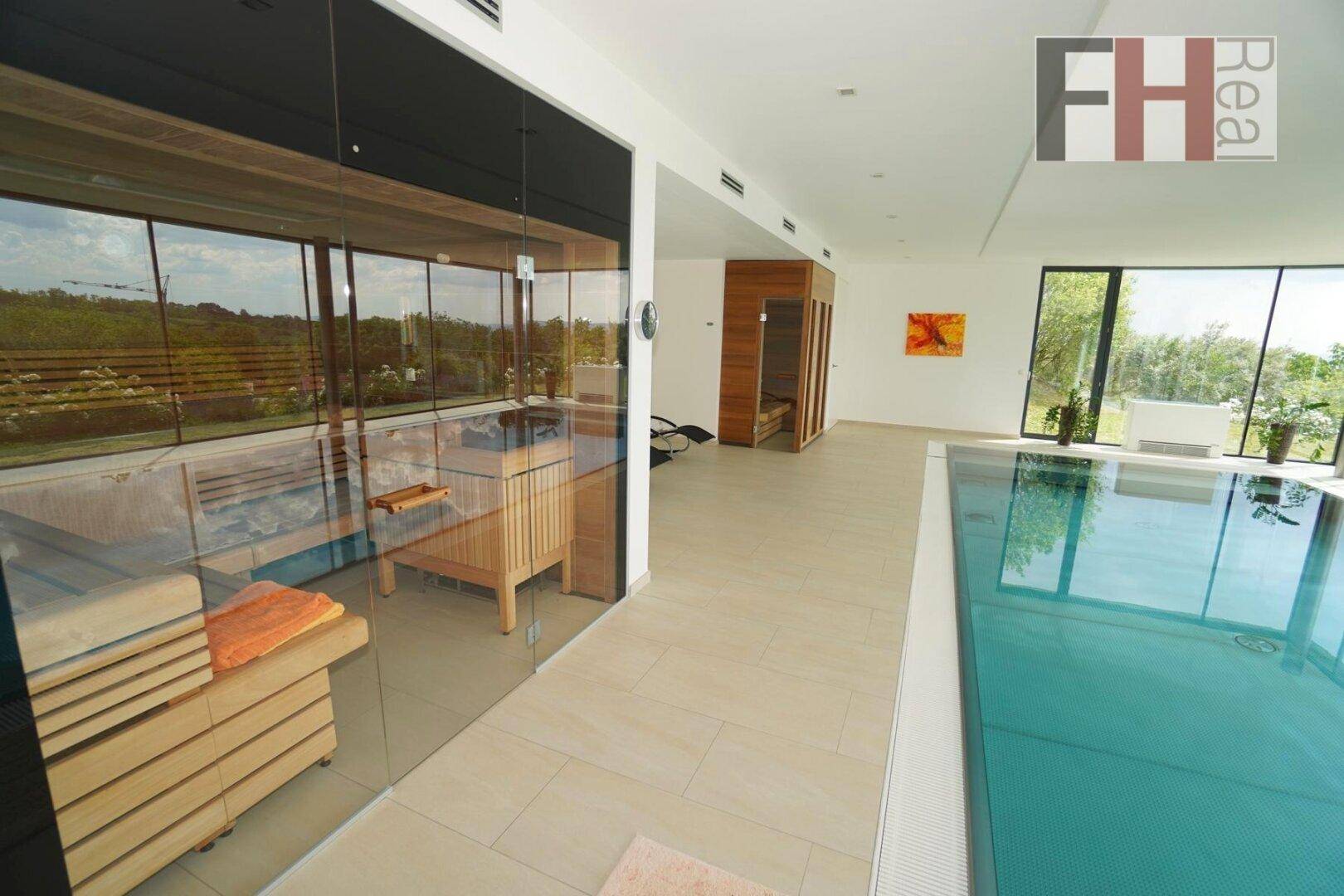 Wellnessbereich mit Sauna, Innenpool und raumhohen Fenstern mit Blick ins Grüne.