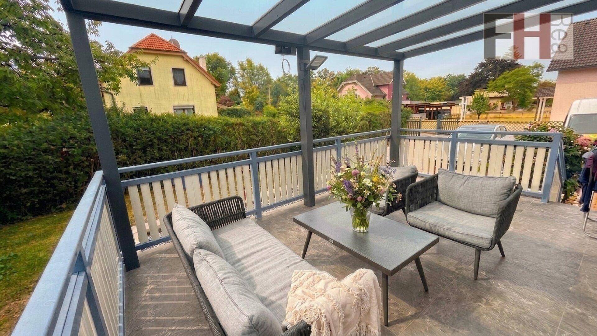Gemütliche überdachte Terrasse mit modernen Gartenmöbeln und Blick ins Grüne.