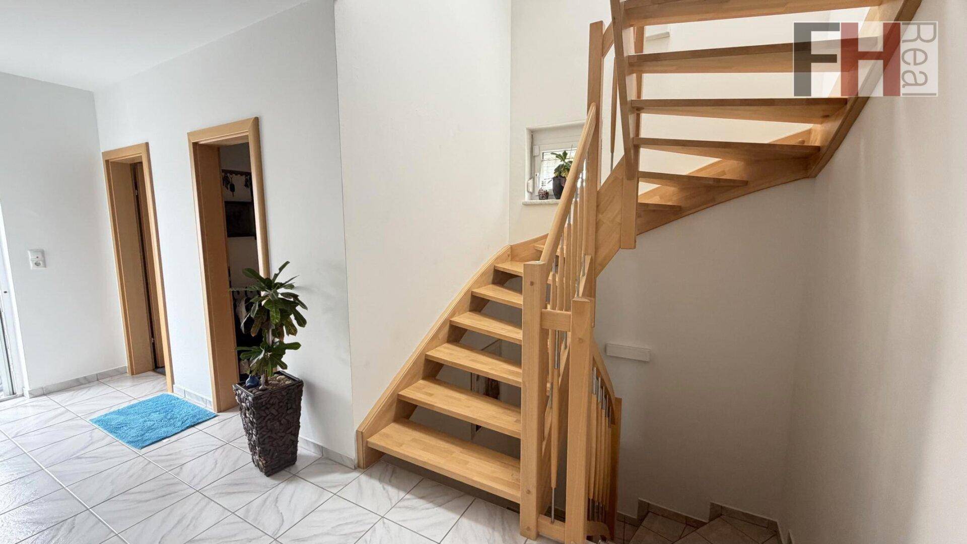 Freundlicher Flur mit Holztreppe, die in die oberen Stockwerke führt.