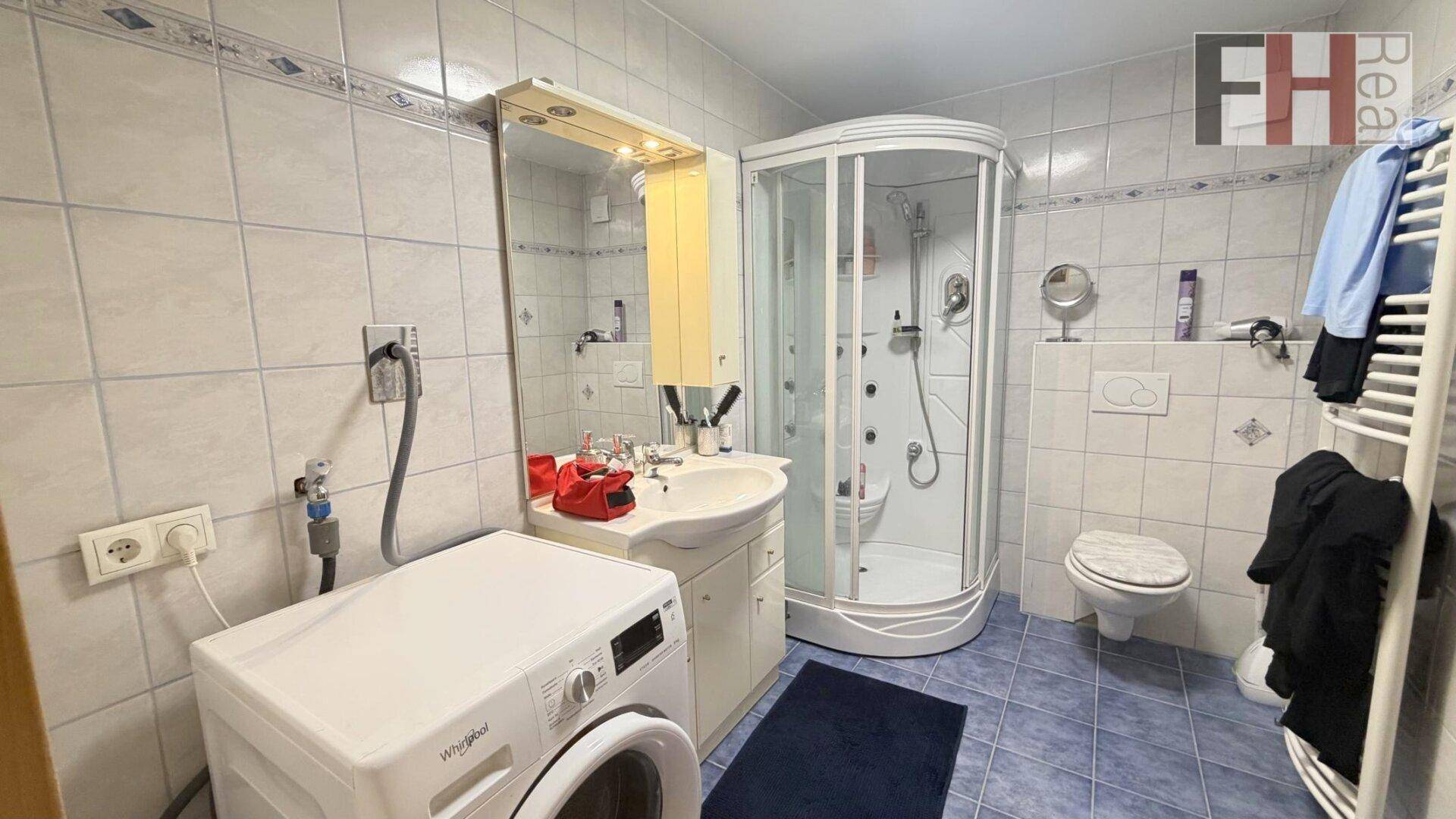 Badezimmer mit Duschkabine, Waschmaschine und beheiztem Handtuchhalter.