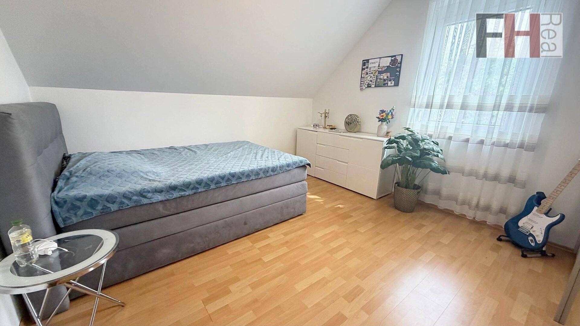 Jugendzimmer mit Einzelbett, Holzboden und Fenster mit viel Tageslicht.