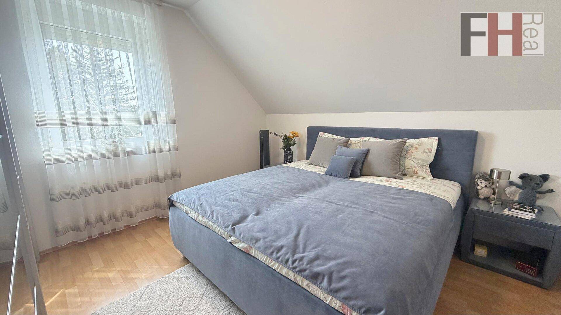 Helles Schlafzimmer mit Doppelbett, Holzboden und Dachschräge.