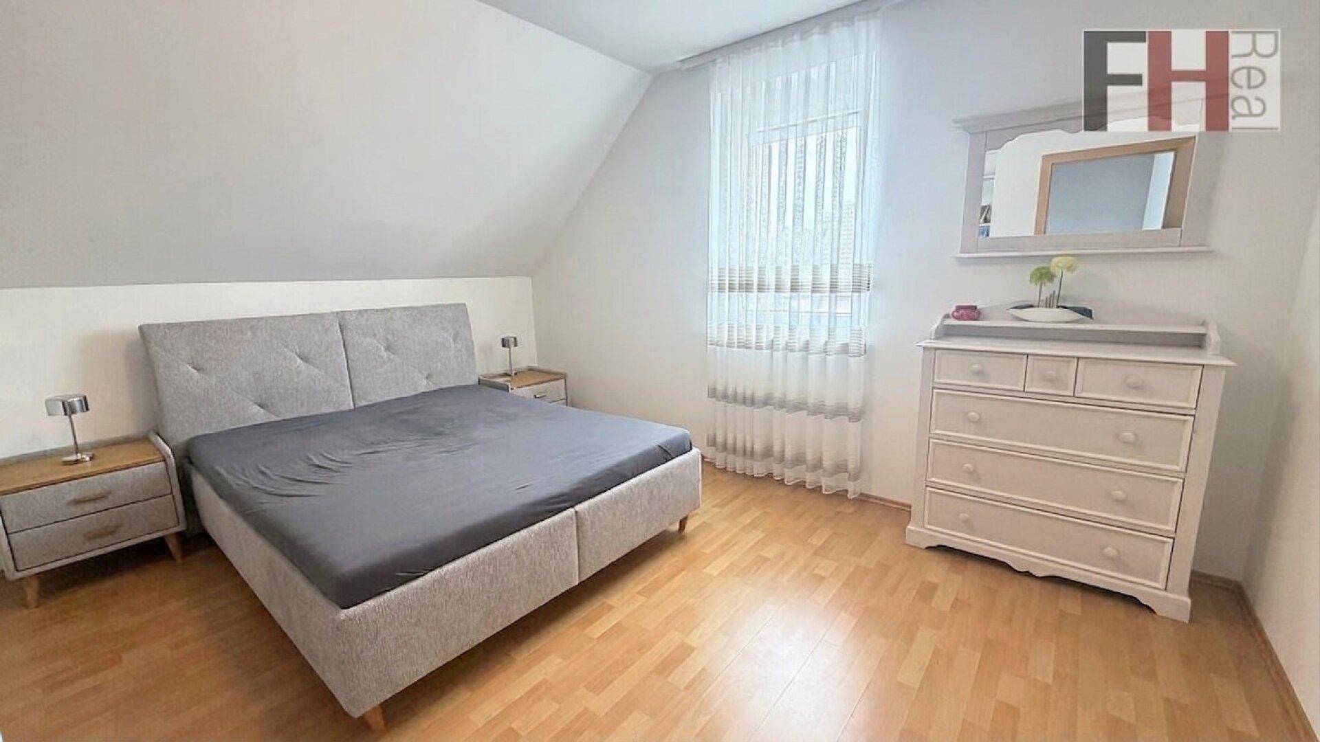 Schlafzimmer mit Doppelbett, Kommode und Holzboden unter der Dachschräge.