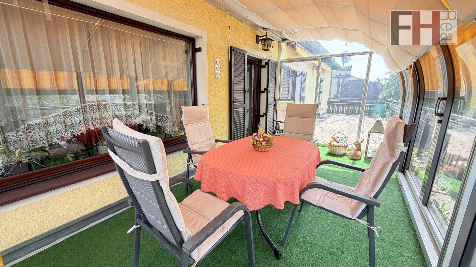 Verglaster Wintergarten mit Sitzgelegenheiten und Blick ins Grüne, ideal für entspannte Stunden.