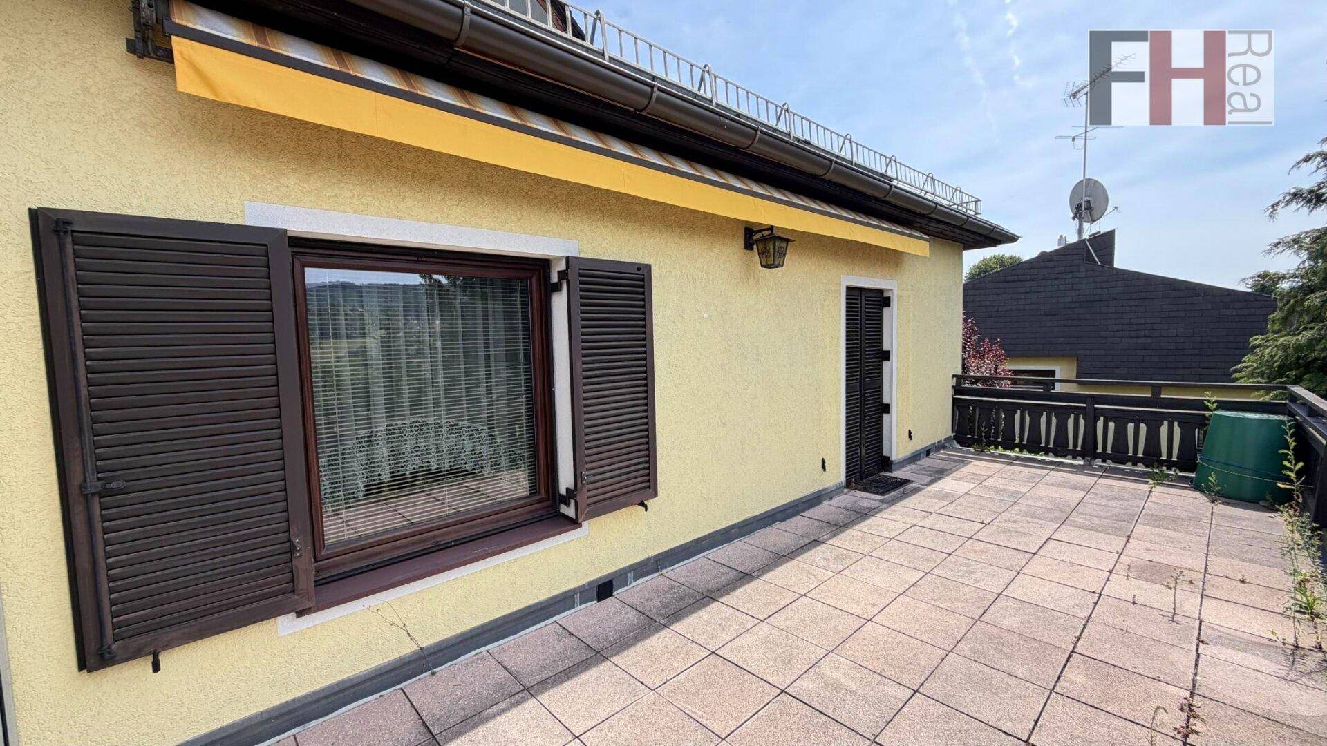 Große, geflieste Terrasse mit Markise und Blick auf die Umgebung, ideal zum Entspannen.