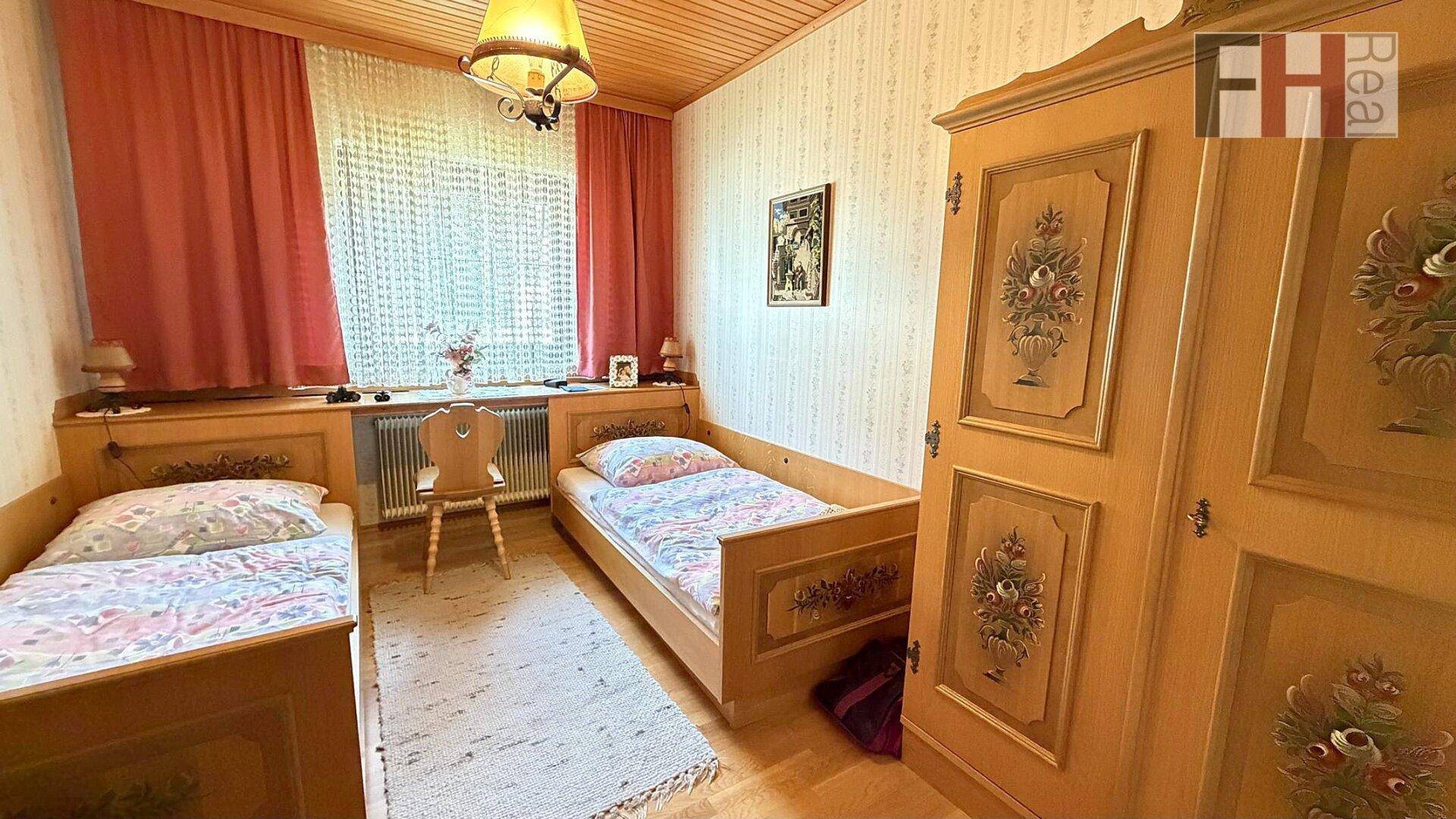 Schlafzimmer im traditionellen Stil mit zwei Einzelbetten, Holzdecke und bemaltem Kleiderschrank.