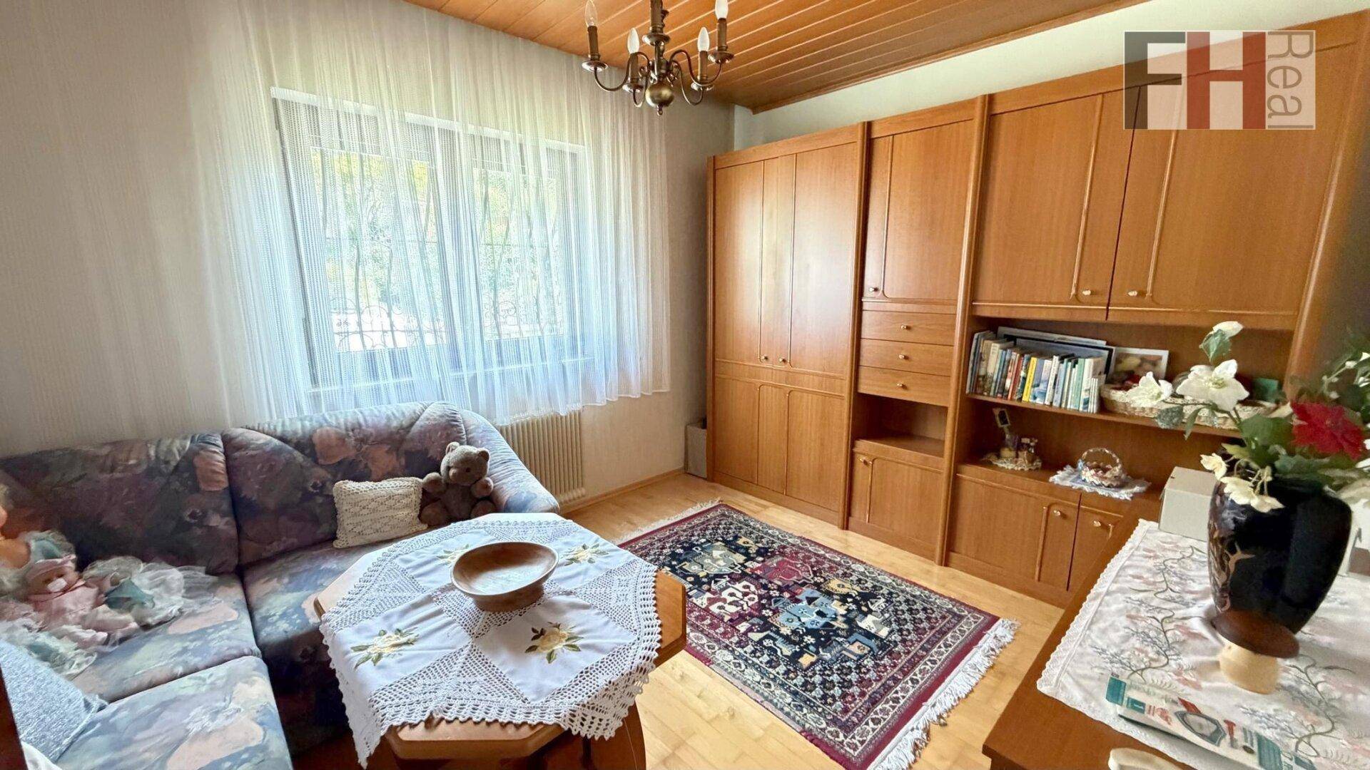 Wohnraum mit Sofa, Holzschränken und Parkettboden, ideal als Gäste- oder Fernsehzimmer.
