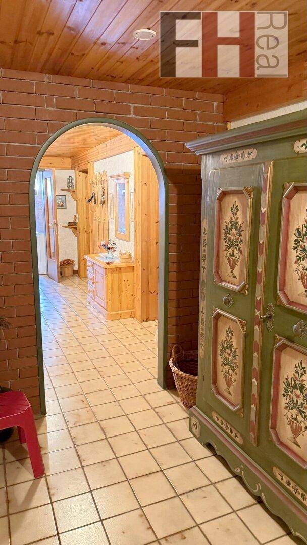 Flur mit Ziegelbogen, Holzdecke und traditionellem Schrank, der in einen weiteren Bereich führt.