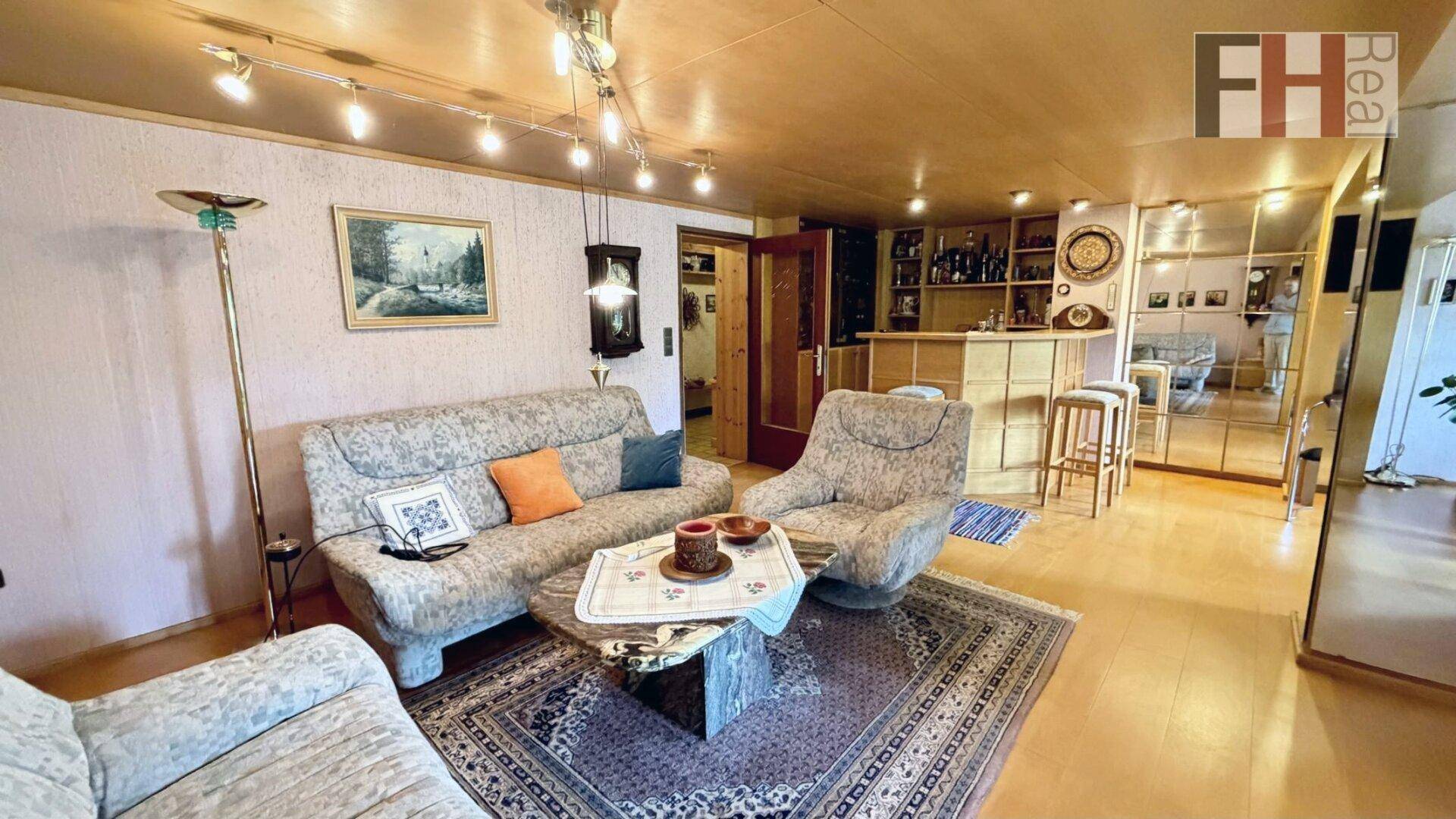 Geräumiges Wohnzimmer mit bequemen Sofas, Parkettboden und einer integrierten Bar.