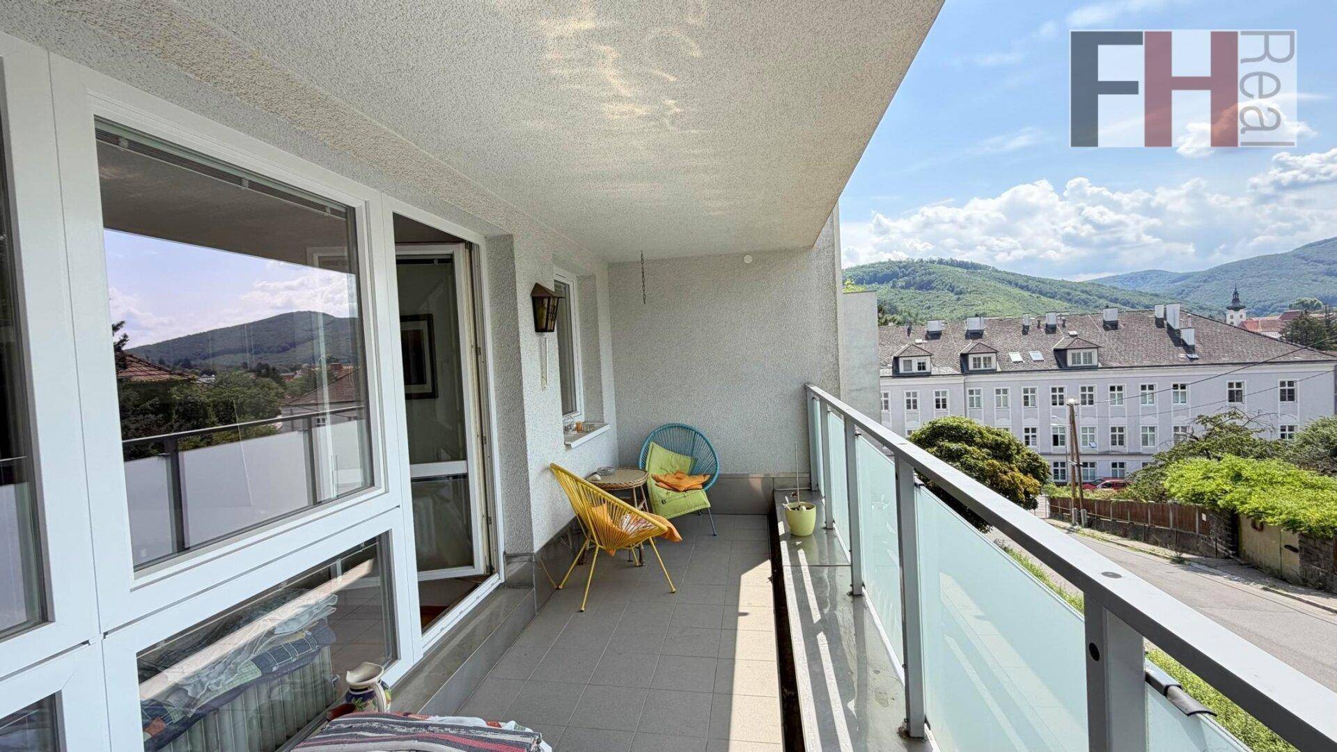 Sonniger Balkon mit Sitzgelegenheiten und weitem Blick über die Stadt und die Natur.