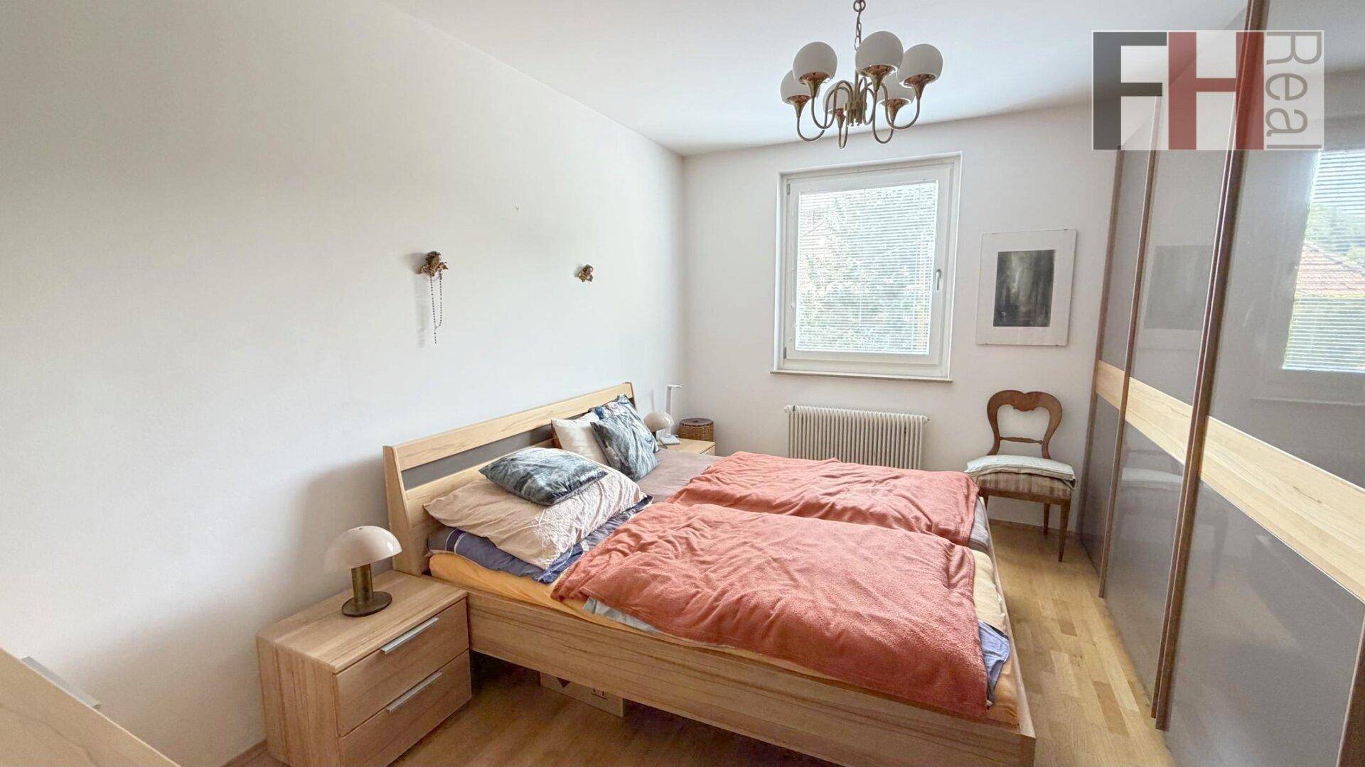 Helles Schlafzimmer mit Doppelbett, Holzmöbeln und einem großen Kleiderschrank.