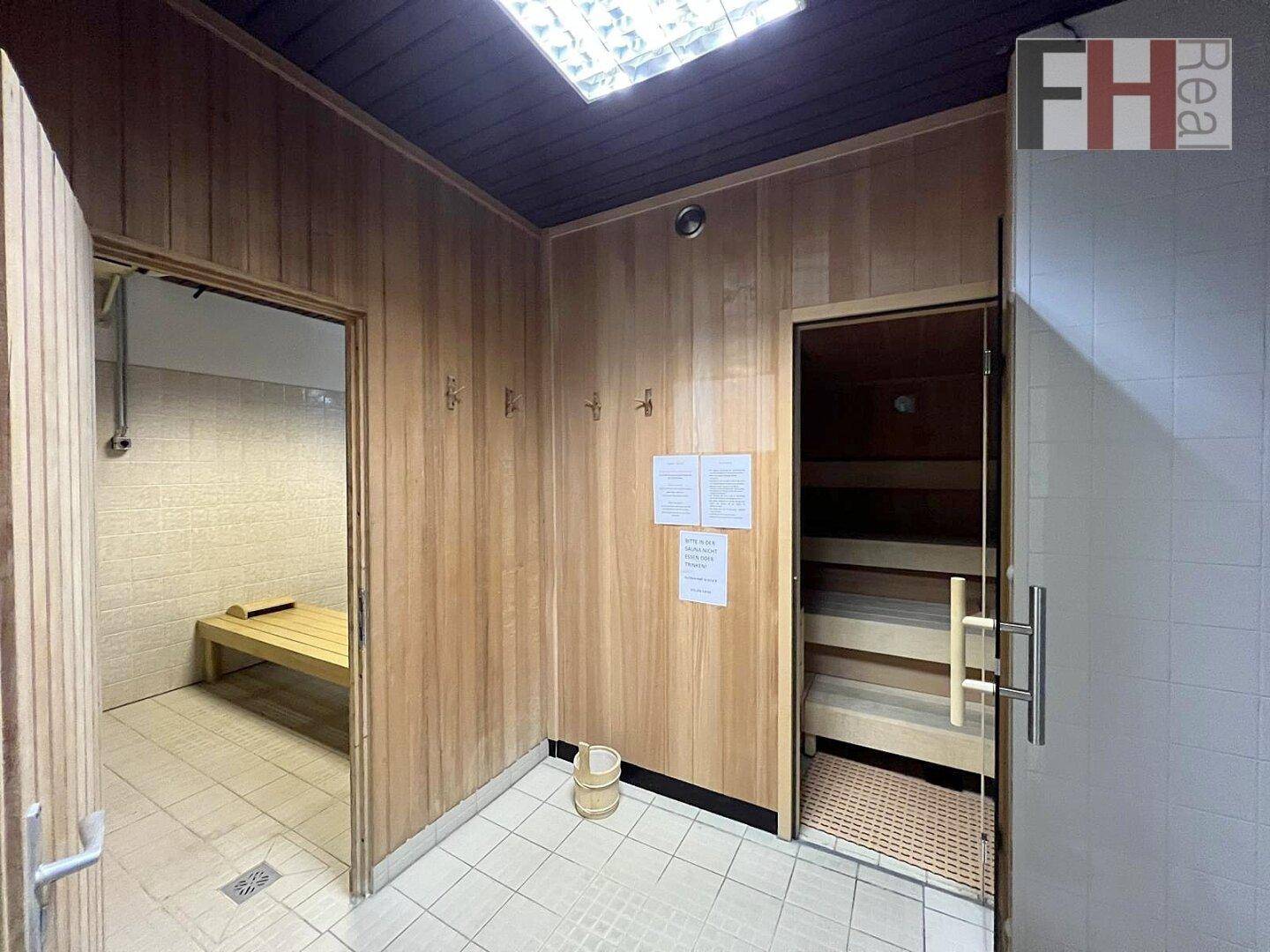 Holzvertäfelte Sauna mit Bänken und angrenzendem Duschbereich für Entspannung.