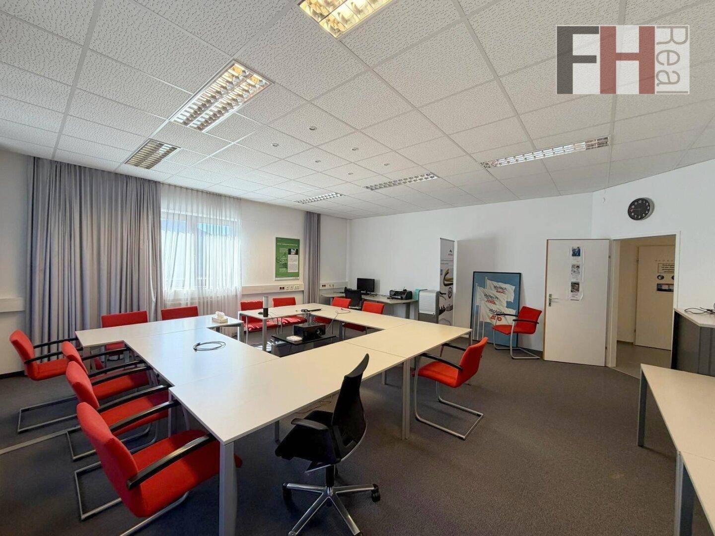Großer Konferenzraum mit U-förmigem Tisch, vielen Stühlen und Teppichboden, ideal für Besprechungen.