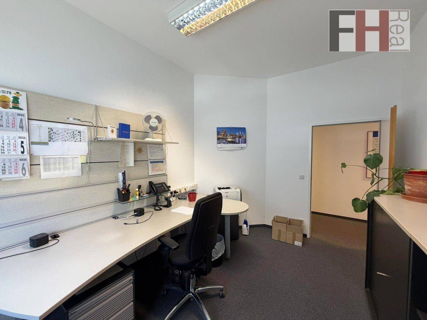 Büro mit Schreibtisch, Bürostuhl und einem offenen Durchgang zu einem weiteren Raum, ideal für Teamarbeit.